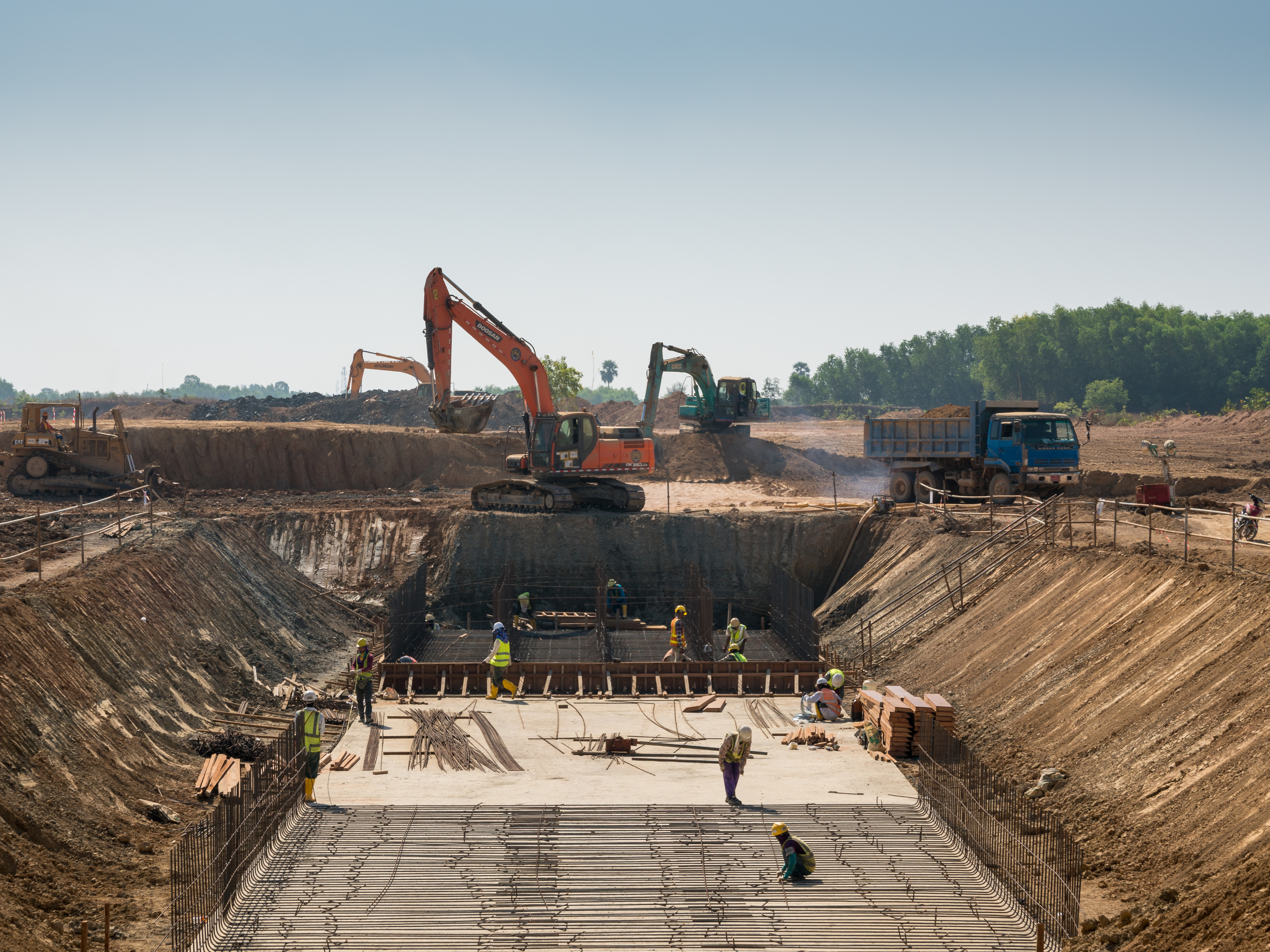 Excavation construction site with workers and heavy machinery
