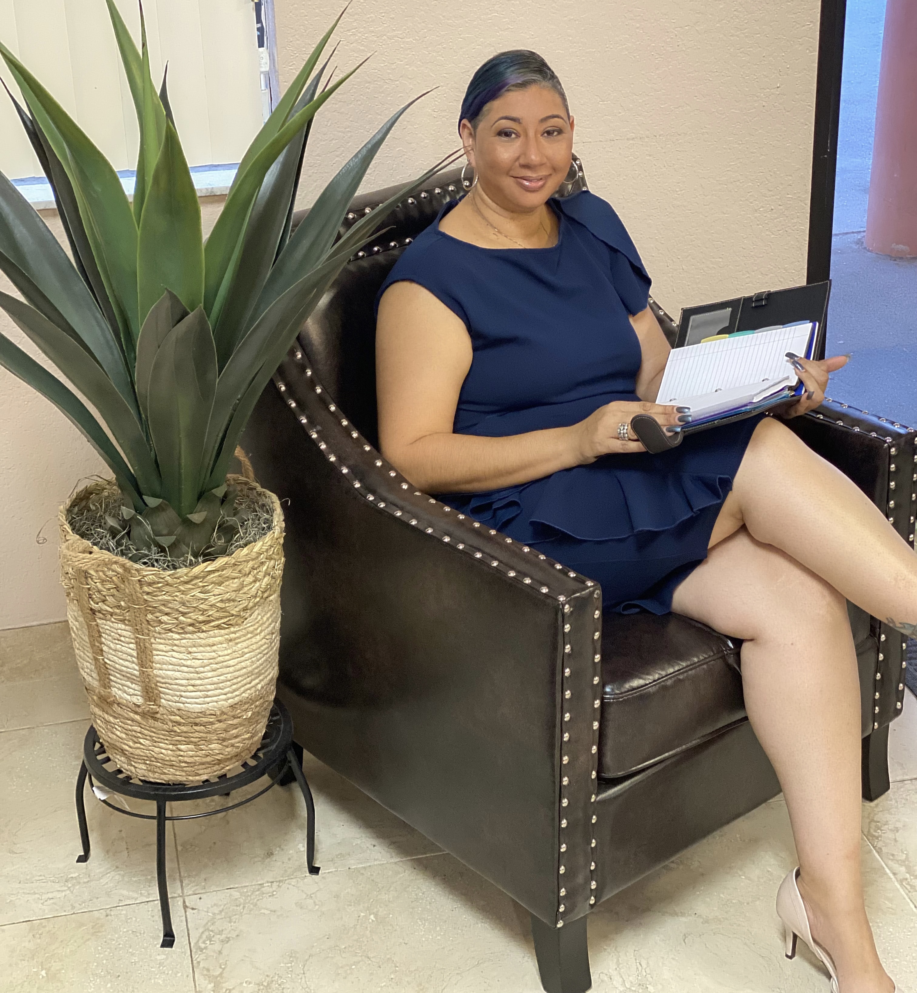 Young lady sitting and confidently holding a day planner, illustrating effective organization and planning for success.