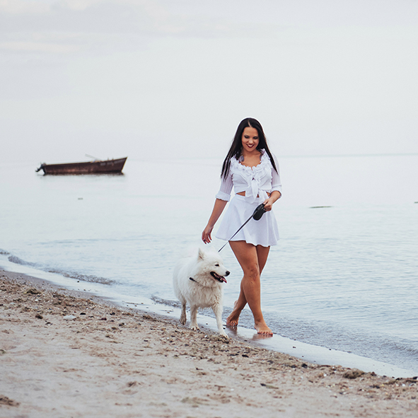 A women playing with her dog, pain free on the beach