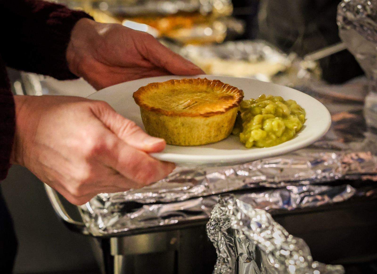 someone holding a plate of pie and peas someone holding a plate of pie and peas
