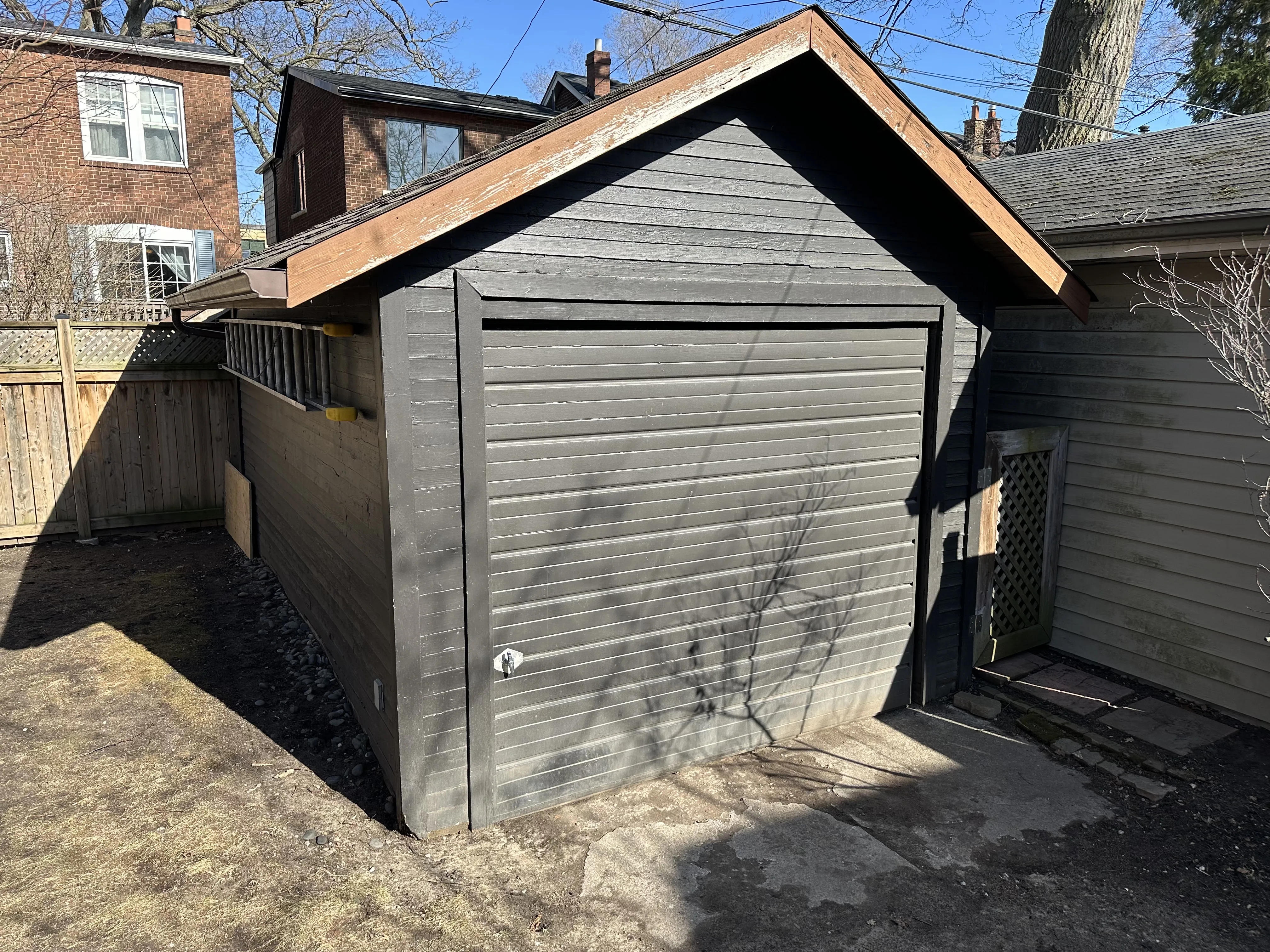 Old detached garage with dark siding and low roof in Toronto before demolition by local garage contractor Old detached garage with dark siding and low roof in Toronto before demolition by local garage contractor