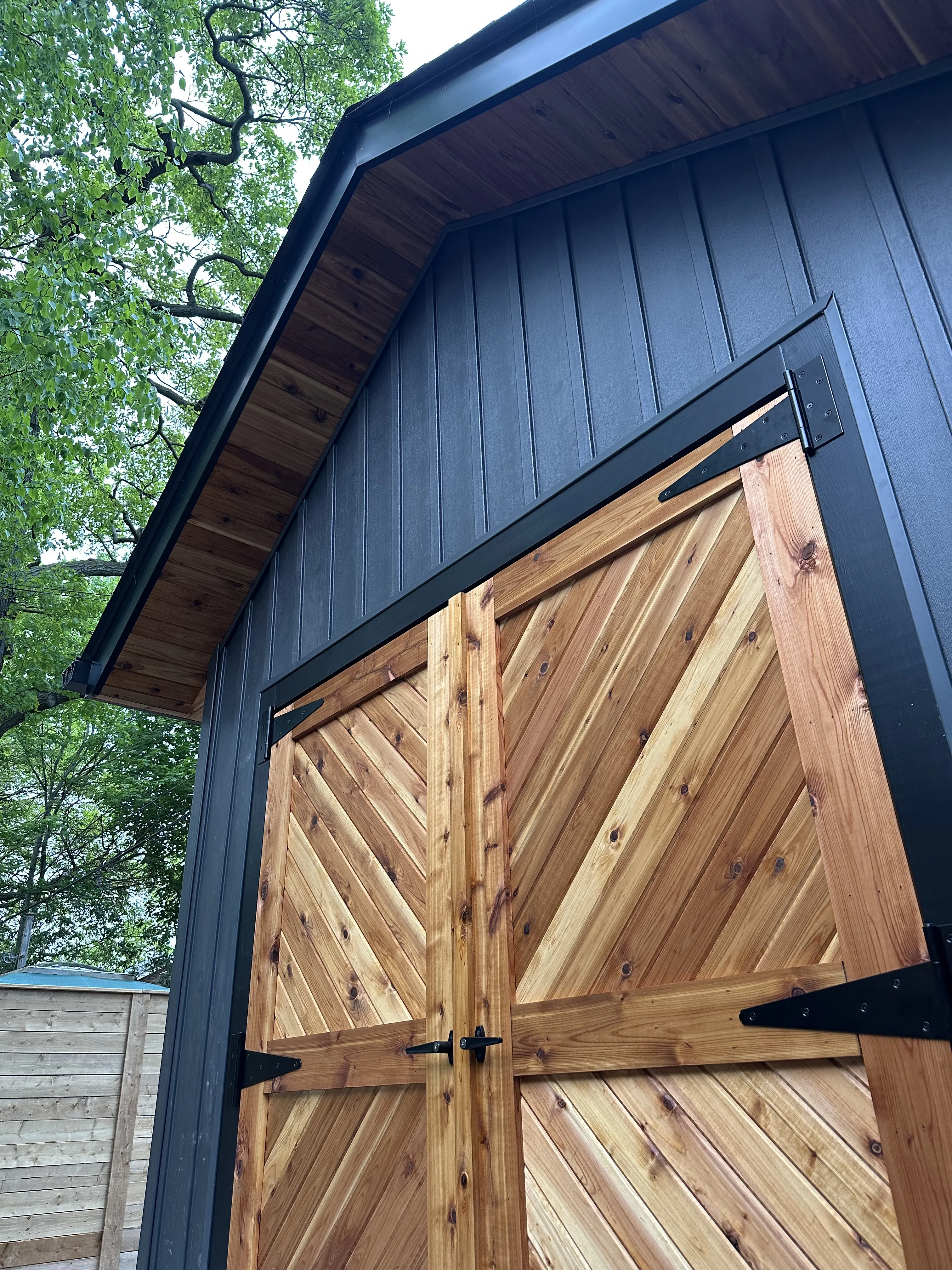 Detailed view of custom cedar chevron-pattern garage doors on rebuilt garage in Toronto Detailed view of custom cedar chevron-pattern garage doors on rebuilt garage in Toronto