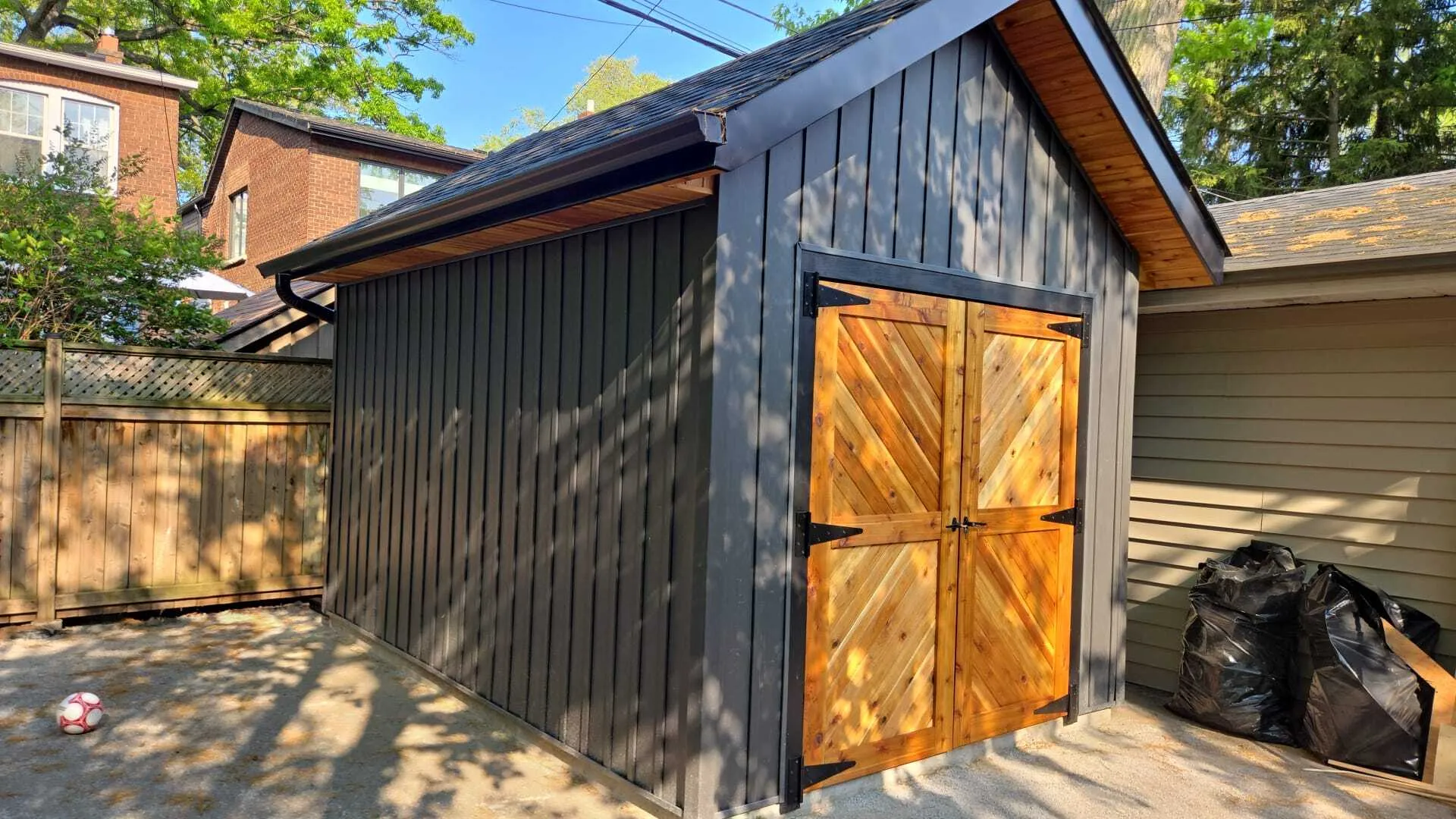 Finished garage rebuild in Toronto with vertical black siding and cedar chevron double doors Finished garage rebuild in Toronto with vertical black siding and cedar chevron double doors