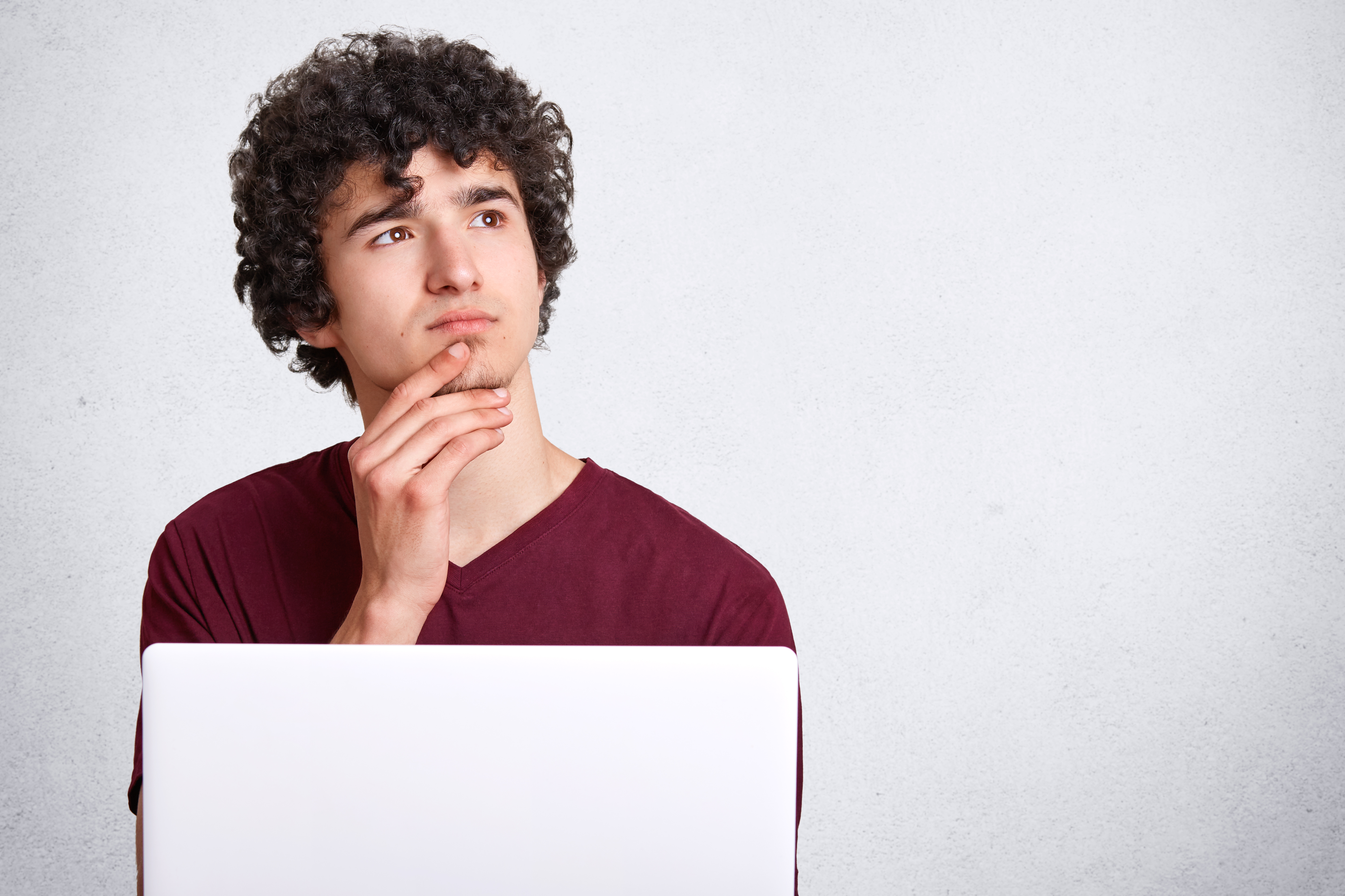 pensive young man thinking how to use google to find online students. pensive young man thinking how to use google to find online students.