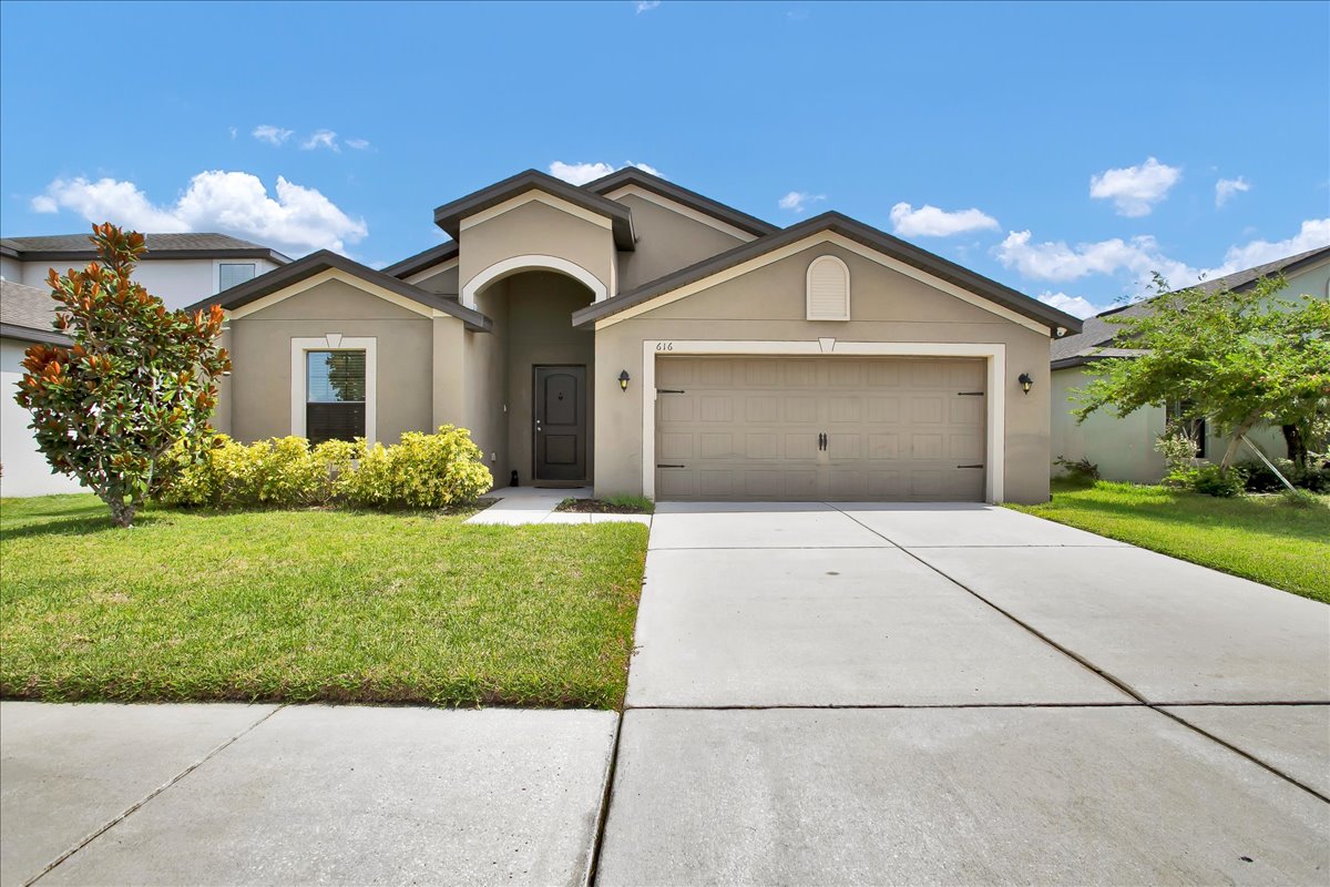 Front exterior of 616 Chatham Walk Dr Ruskin FL – 4 bedroom home with solar panels, garage, and landscaped yard