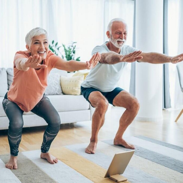 Happy older couple doing yoga and experiencing improved mobility, energy, and wellness through hormone optimization at Hormone Treatment Centers in Overland Park, KS.