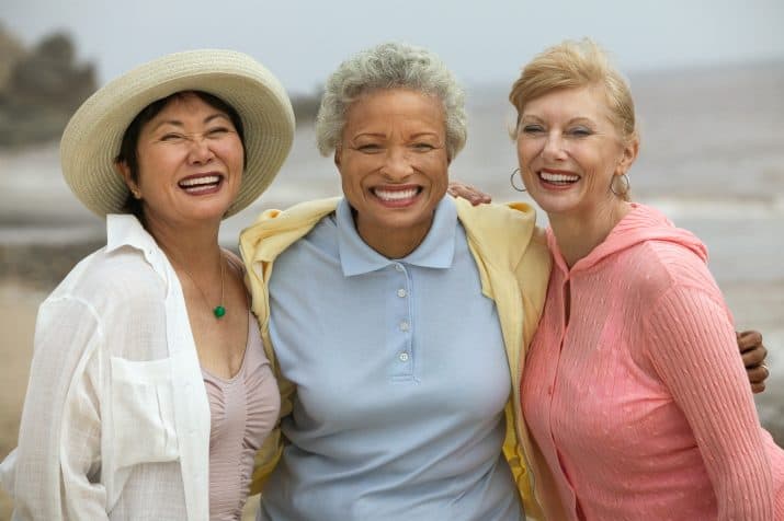 three smiling women of different ethnicity standing together