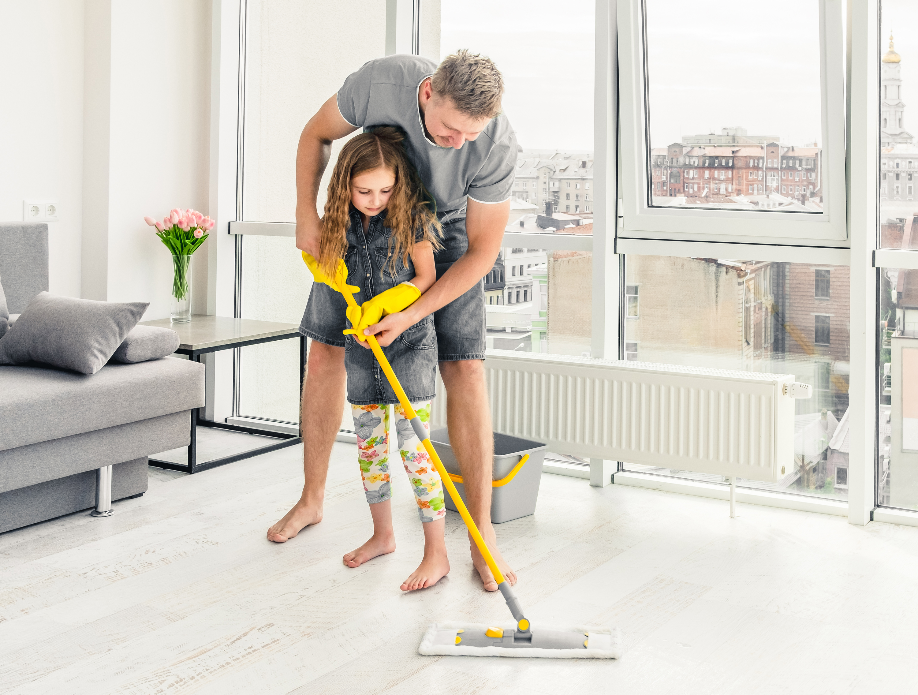 child and mom holding cleaning supplies