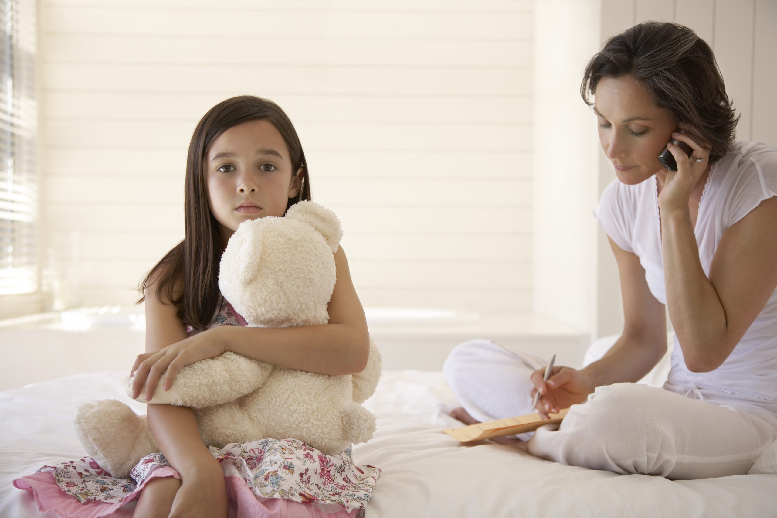 woman on phone while daughter looks on with sad look