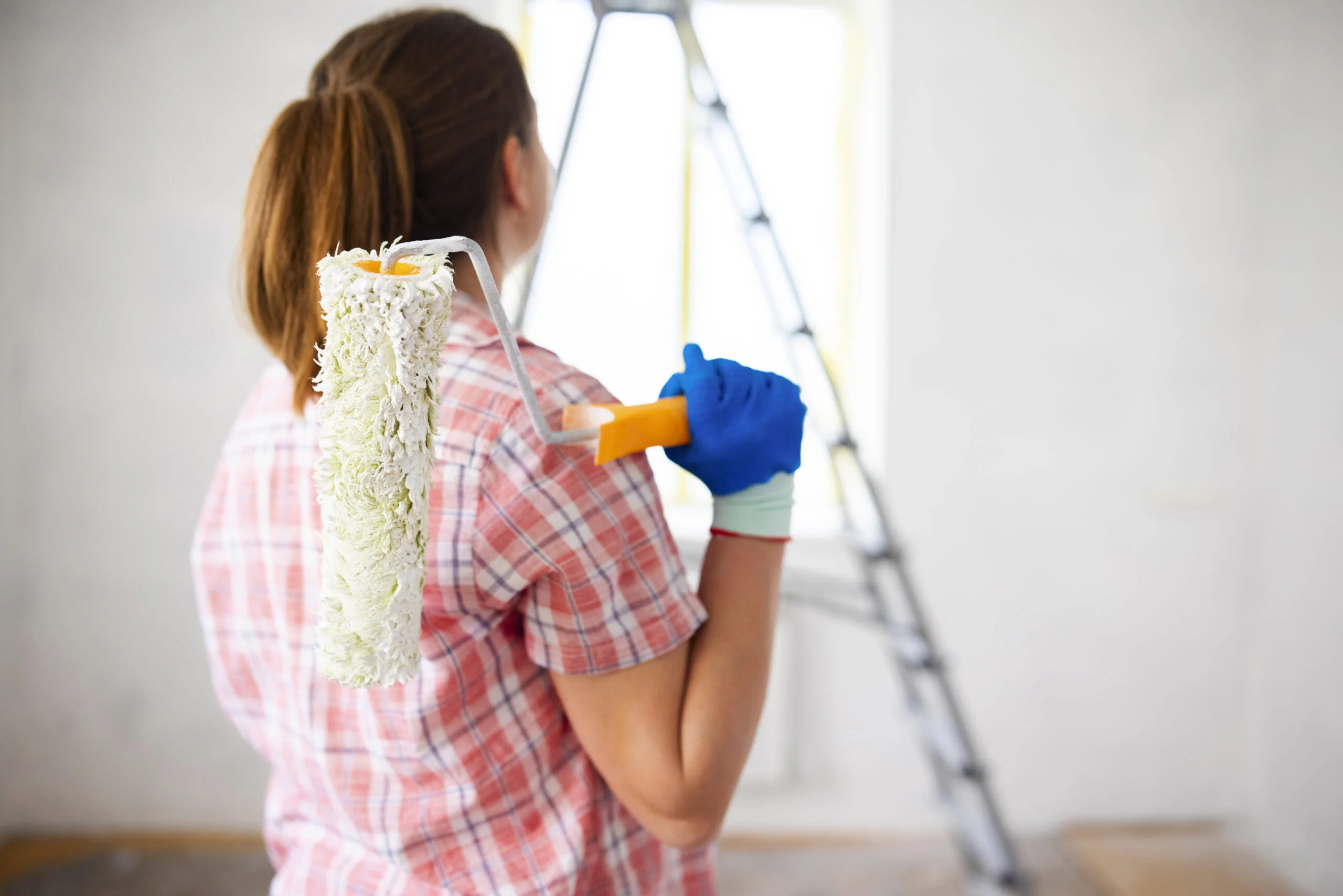 woman holding dirty roller after painting walls in room