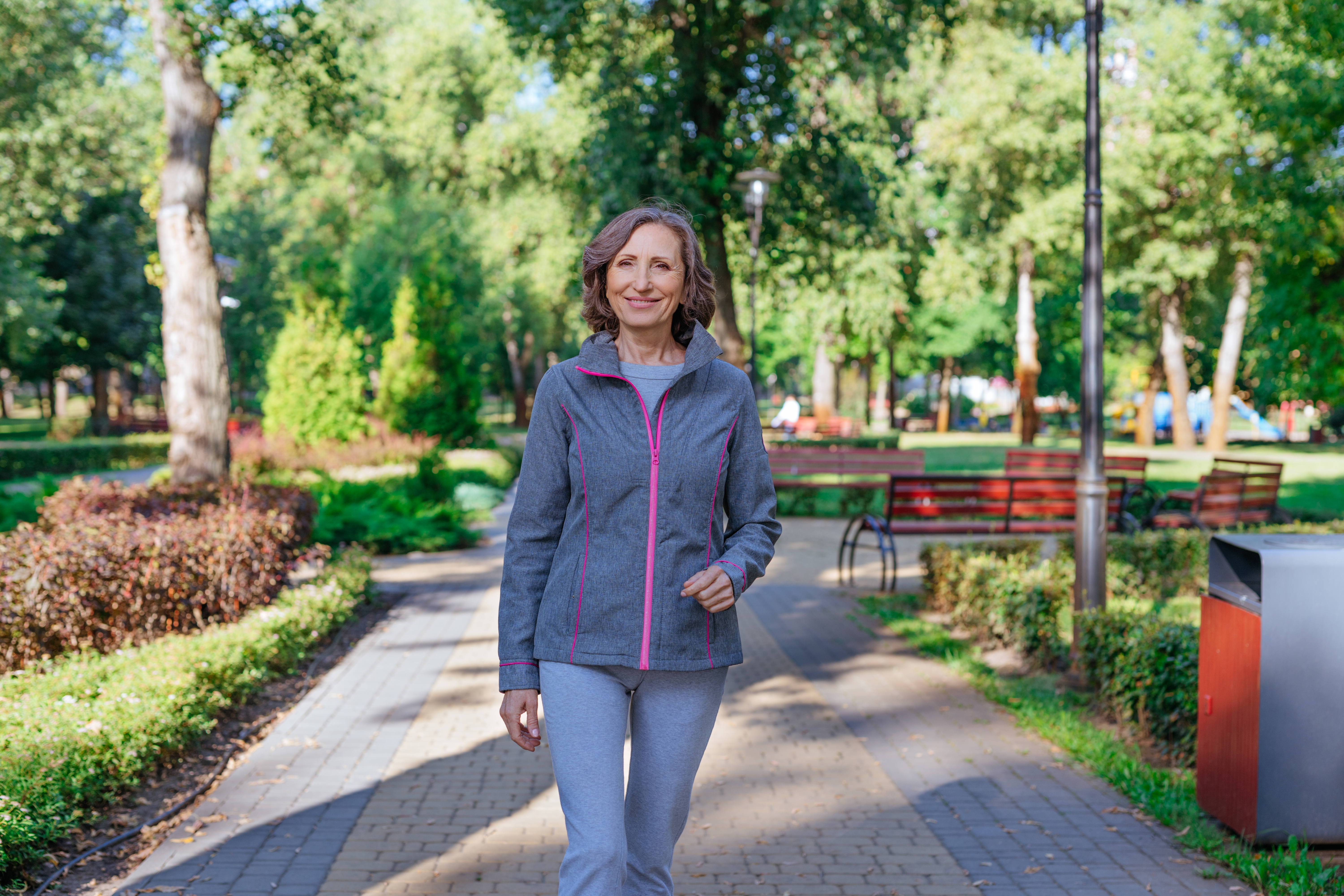 Happy mature woman walking in the park outdoor after weight loss Happy mature woman walking in the park outdoor after weight loss