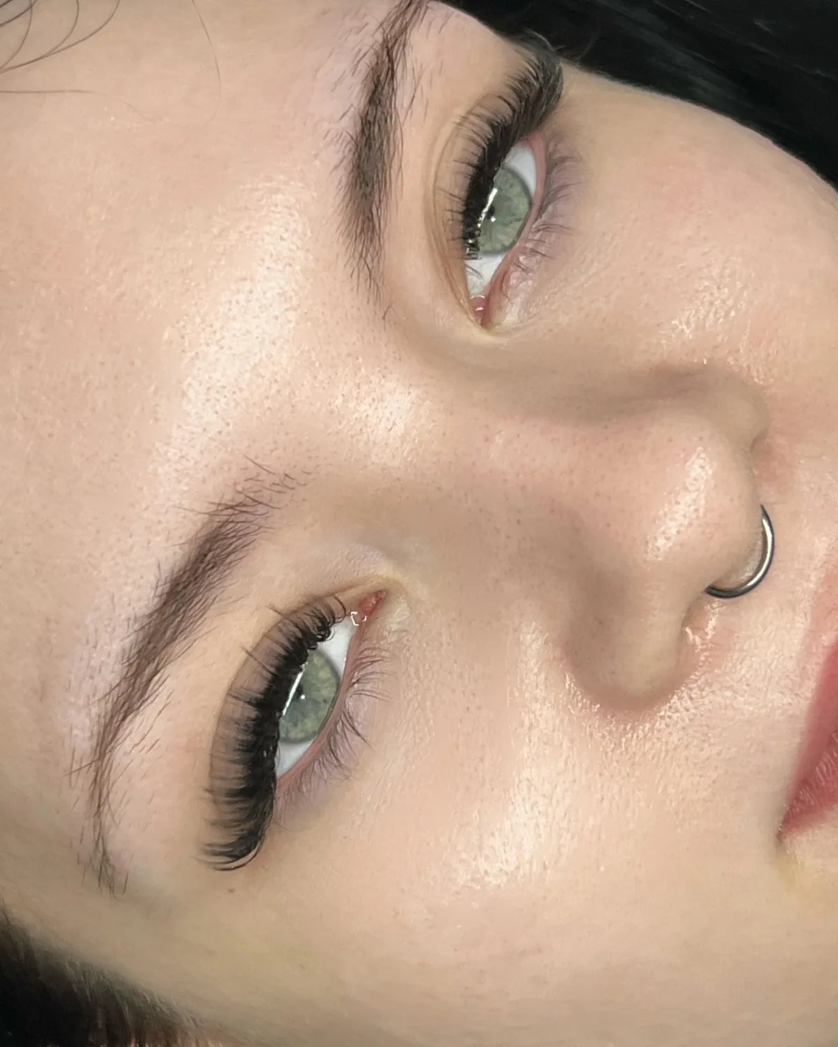 A close up of a woman 's face with a nose ring.