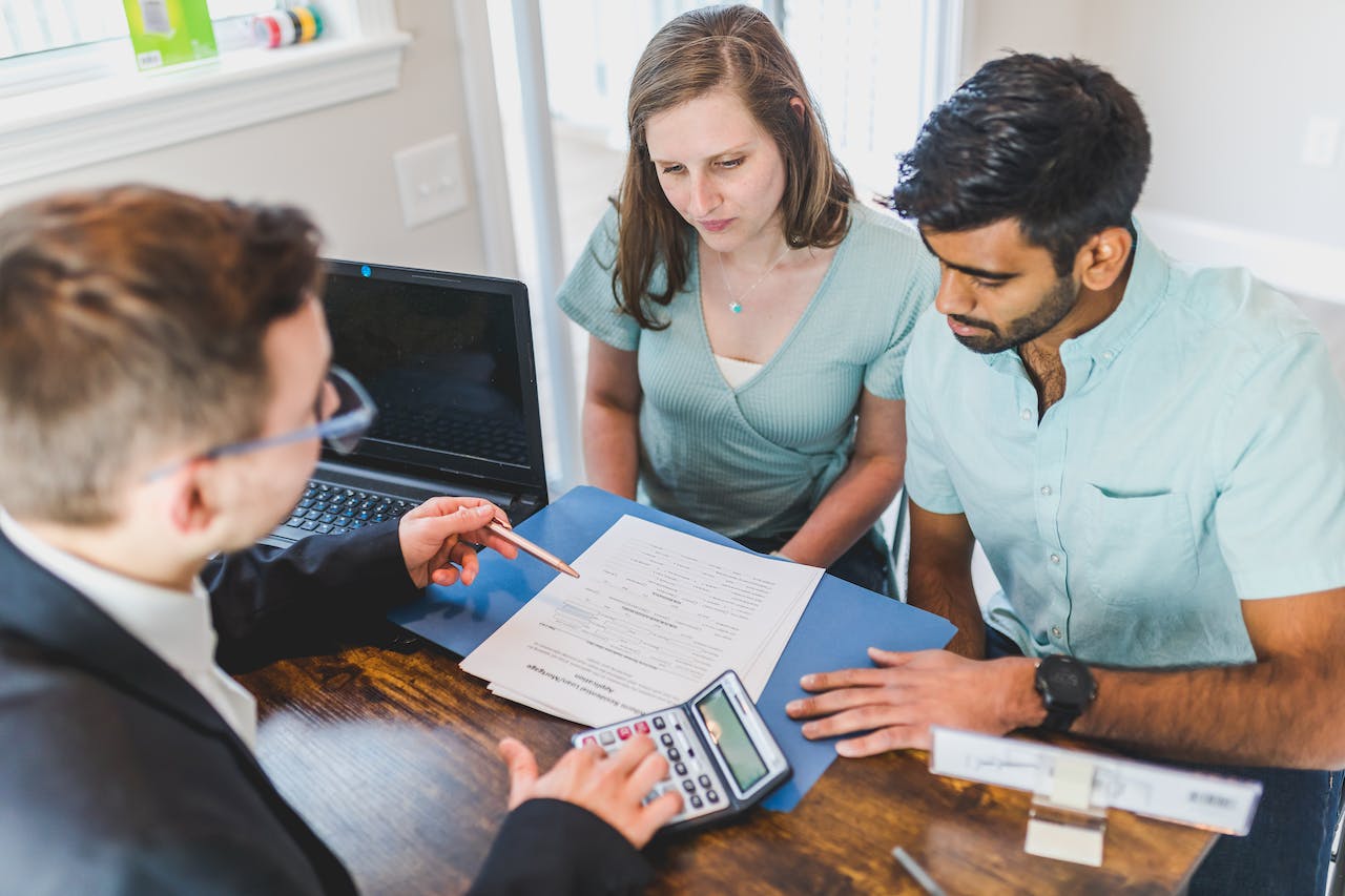 real estate agent in black coat discussing an agreement to a couple real estate agent in black coat discussing an agreement to a couple