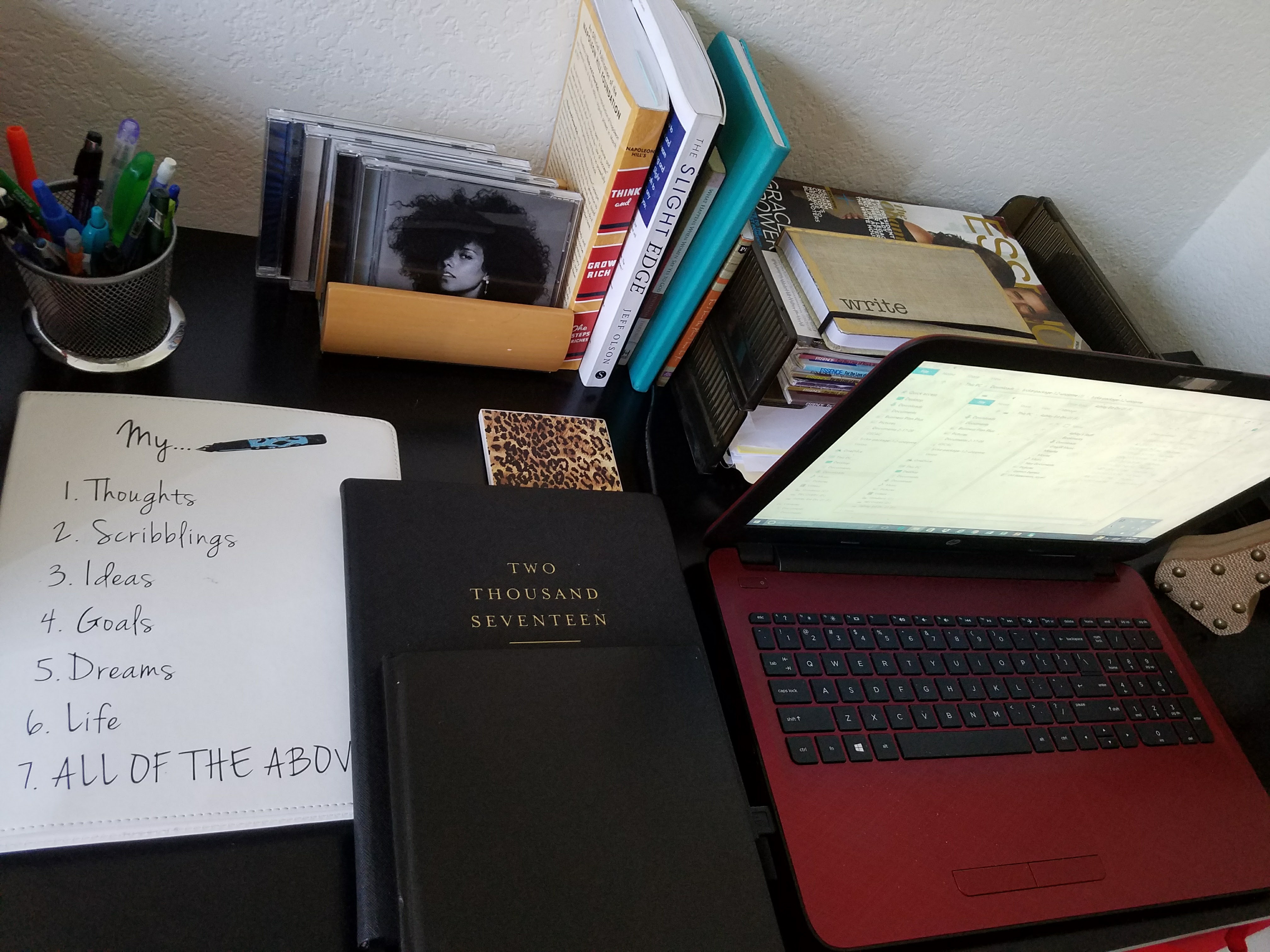 Photo of a 2017 desk setup with a red laptop, journals, and inspirational books, symbolizing the early hustle behind a dream not yet shared.
