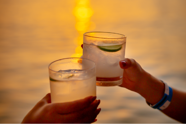 Copa de cóctel con el sol poniente de fondo desde la cubierta del catamarán en el Bahía Sunset Day Pass.