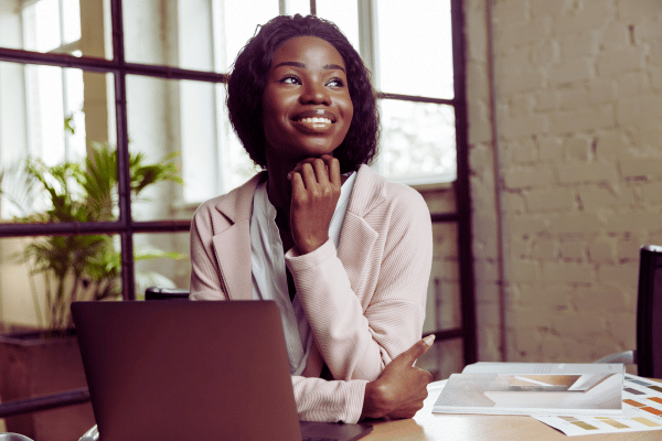 Woman looking happy in front of laptop representing the confidence that can result from working with a tech coach Woman looking happy in front of laptop representing the confidence that can result from working with a tech coach