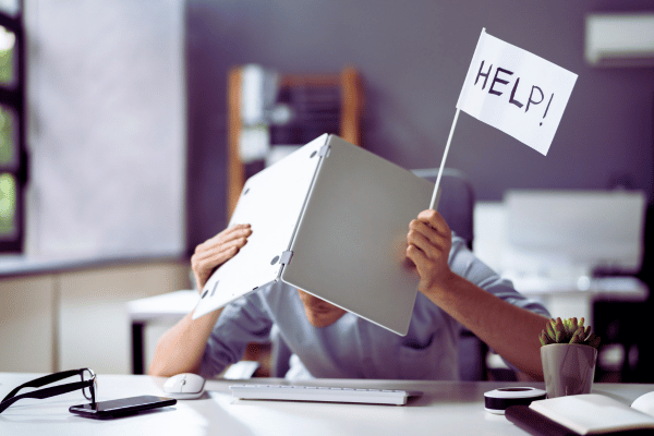 Man hiding under mac device, waving flag with "help!" written on it. If your inbox is overflowing the first step is an email detox Man hiding under mac device, waving flag with "help!" written on it. If your inbox is overflowing the first step is an email detox