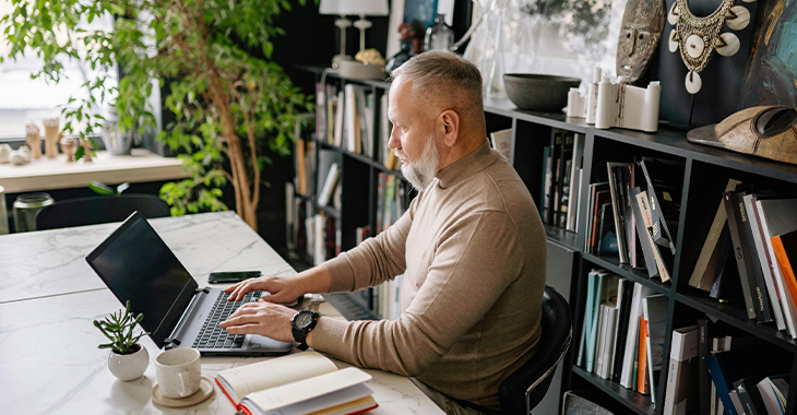 Man sitting at a desk, writing down goals in a notebook, focusing on setting realistic objectives for stress management and personal growth. Man sitting at a desk, writing down goals in a notebook, focusing on setting realistic objectives for stress management and personal growth.