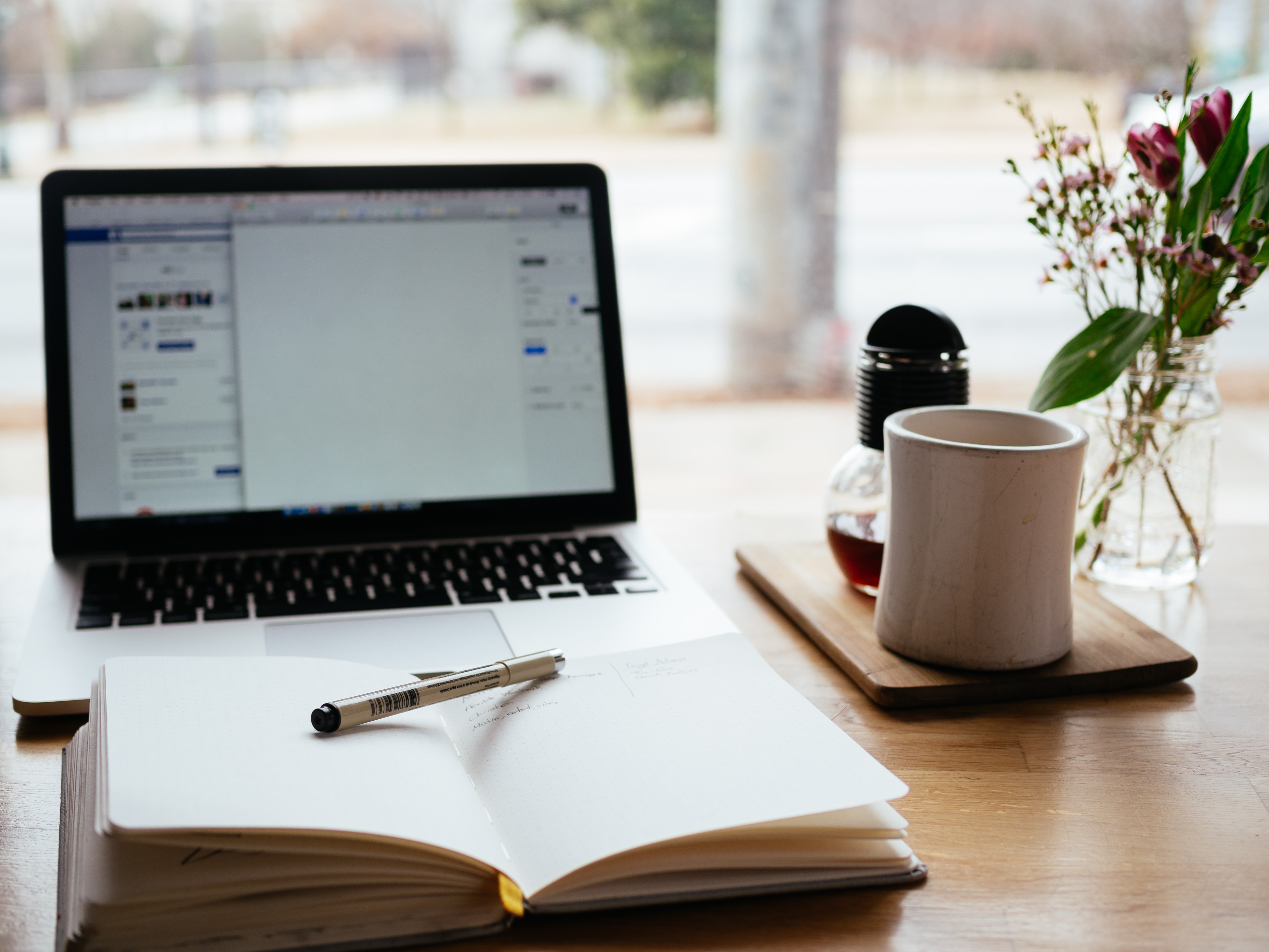 picture of a notebook with a pen on it and a macbook in the background