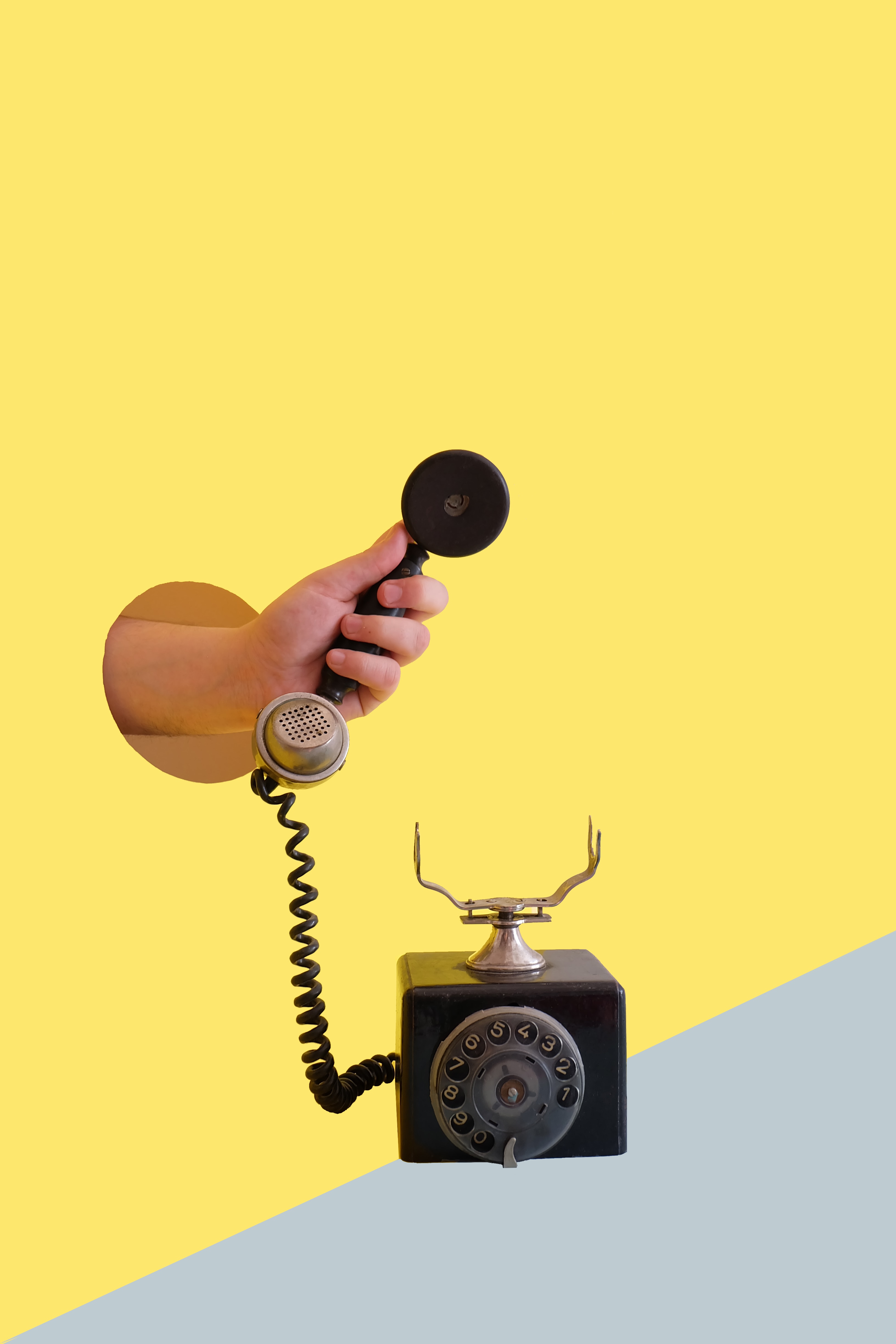 man's hand holding a telephone on a yellow background