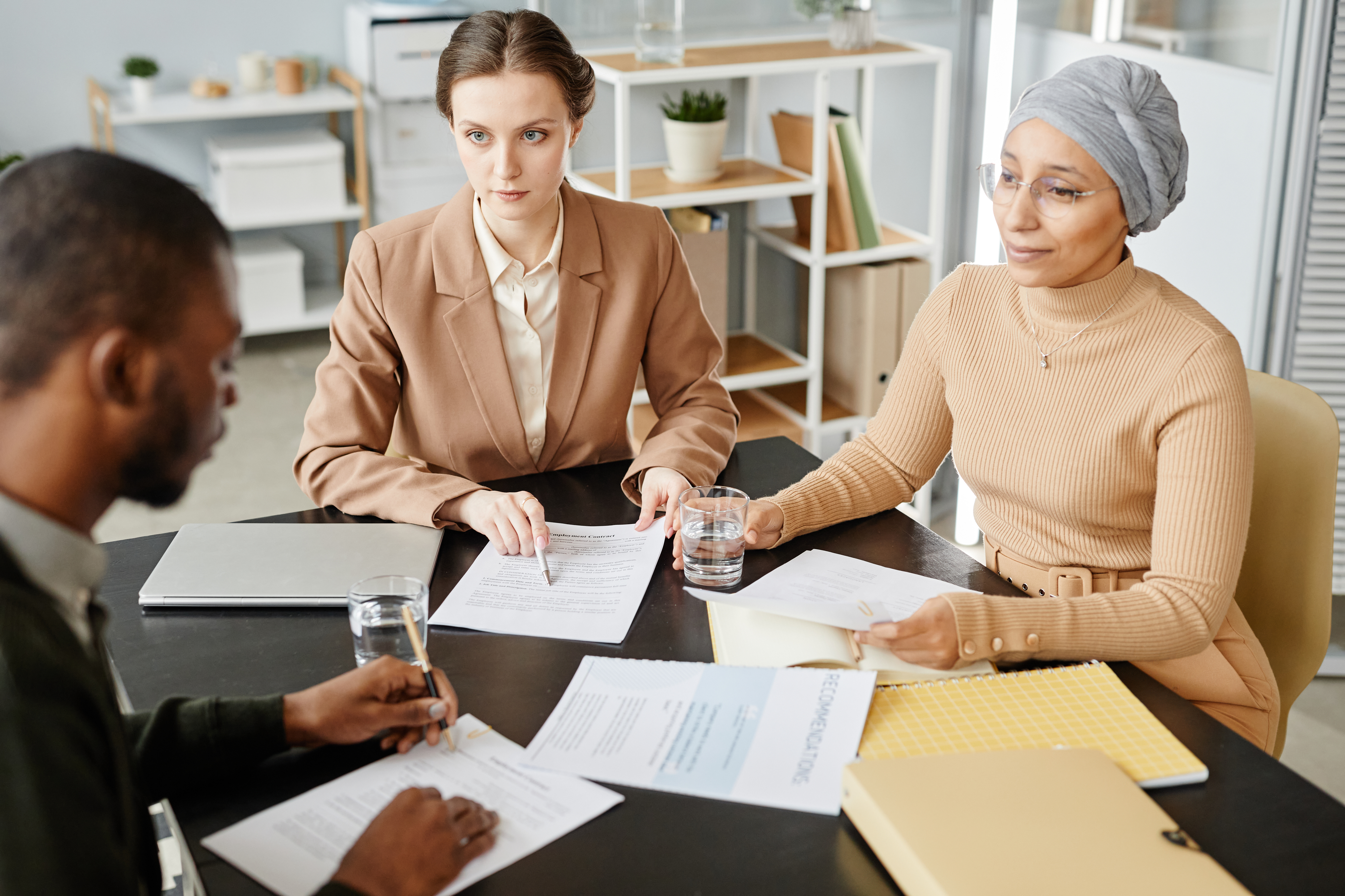 A diverse group of professionals engaged in a business meeting, reviewing documents and discussing strategies, representing collaboration and inclusion in the workplace.