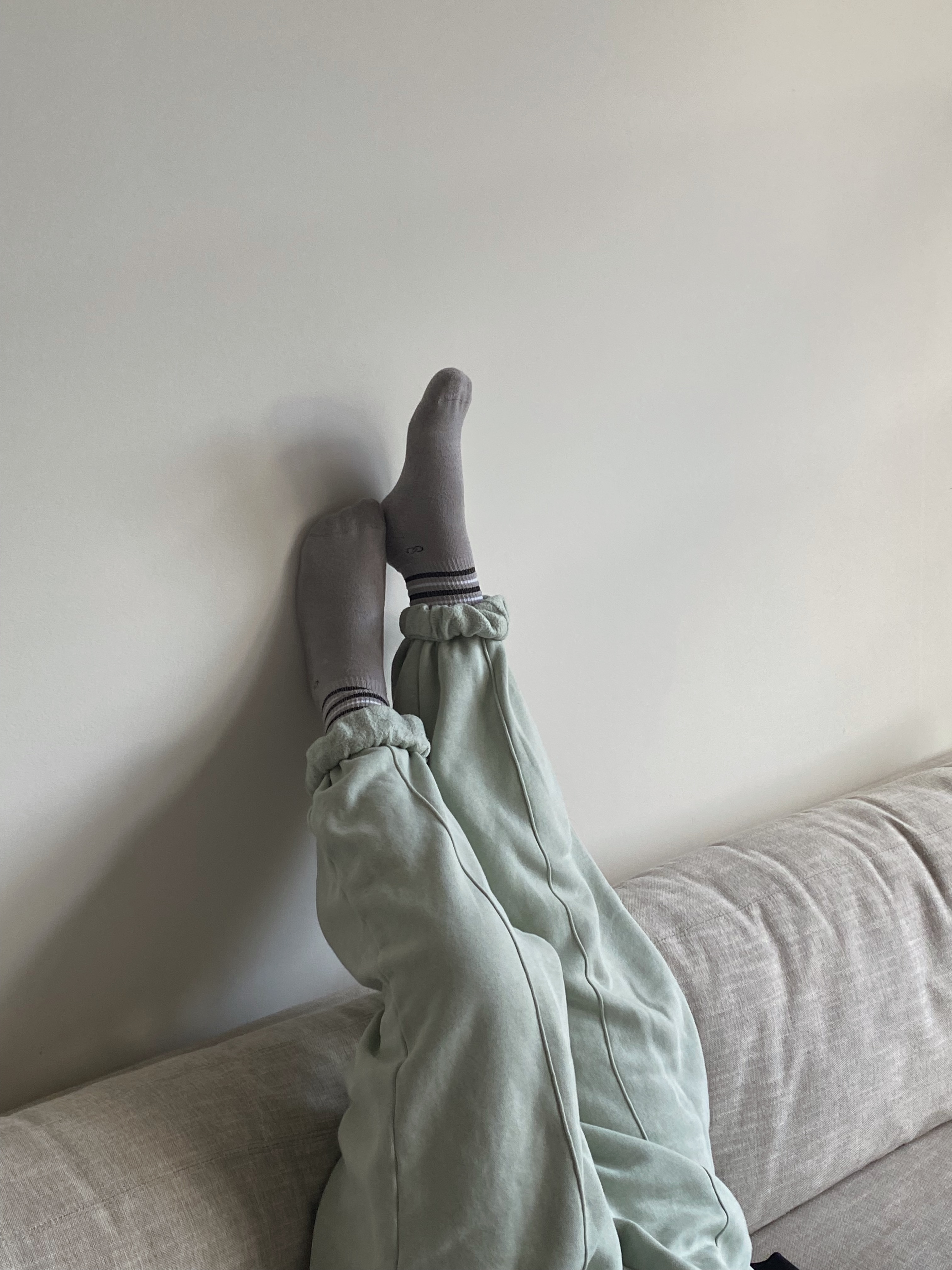 Woman embracing her alcohol-free lifestyle while legs are up the wall in wool socks Woman embracing her alcohol-free lifestyle while legs are up the wall in wool socks