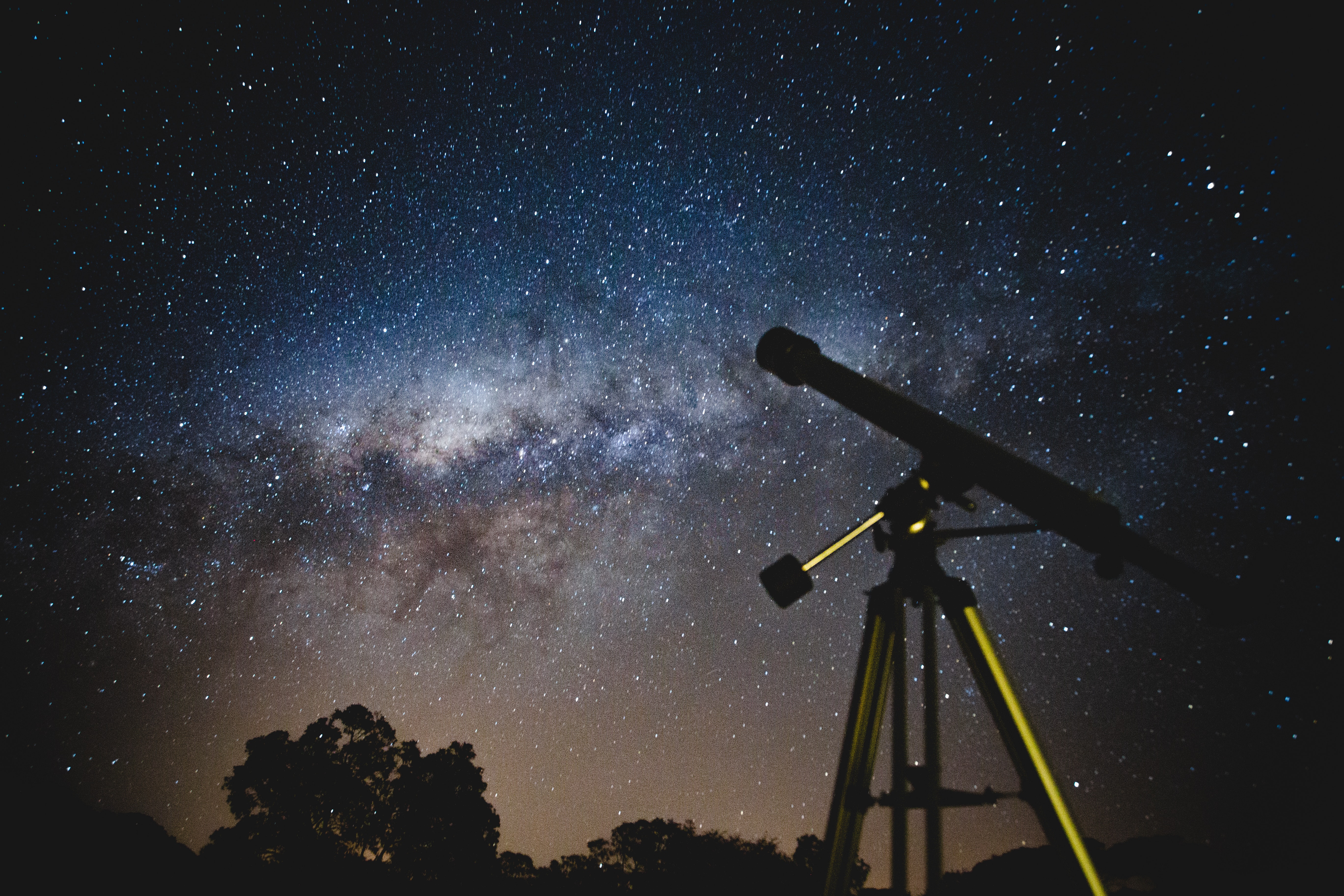 vast night sky with lots of stars and a telescope