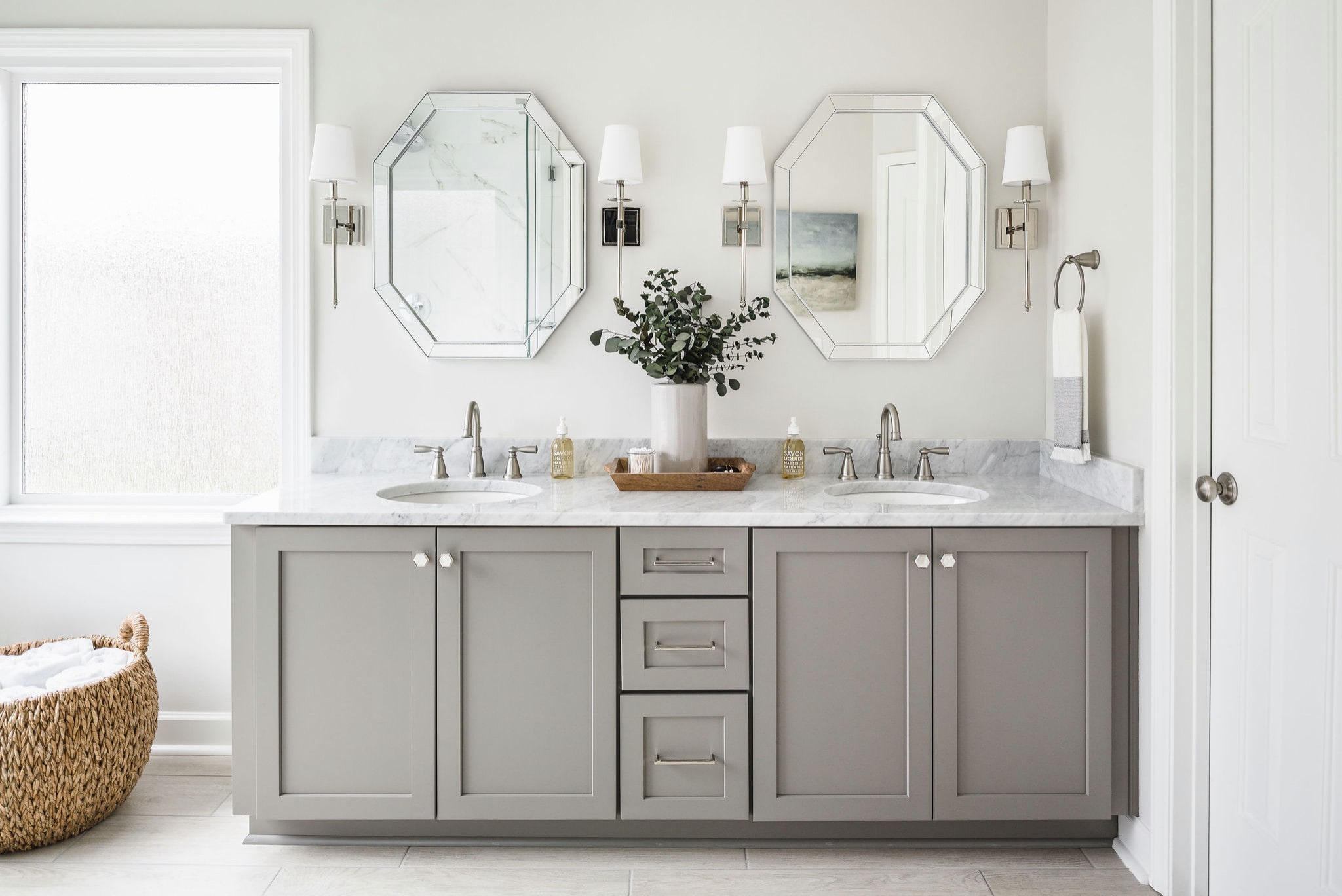 a bathroom with grey cabinets and mirrors