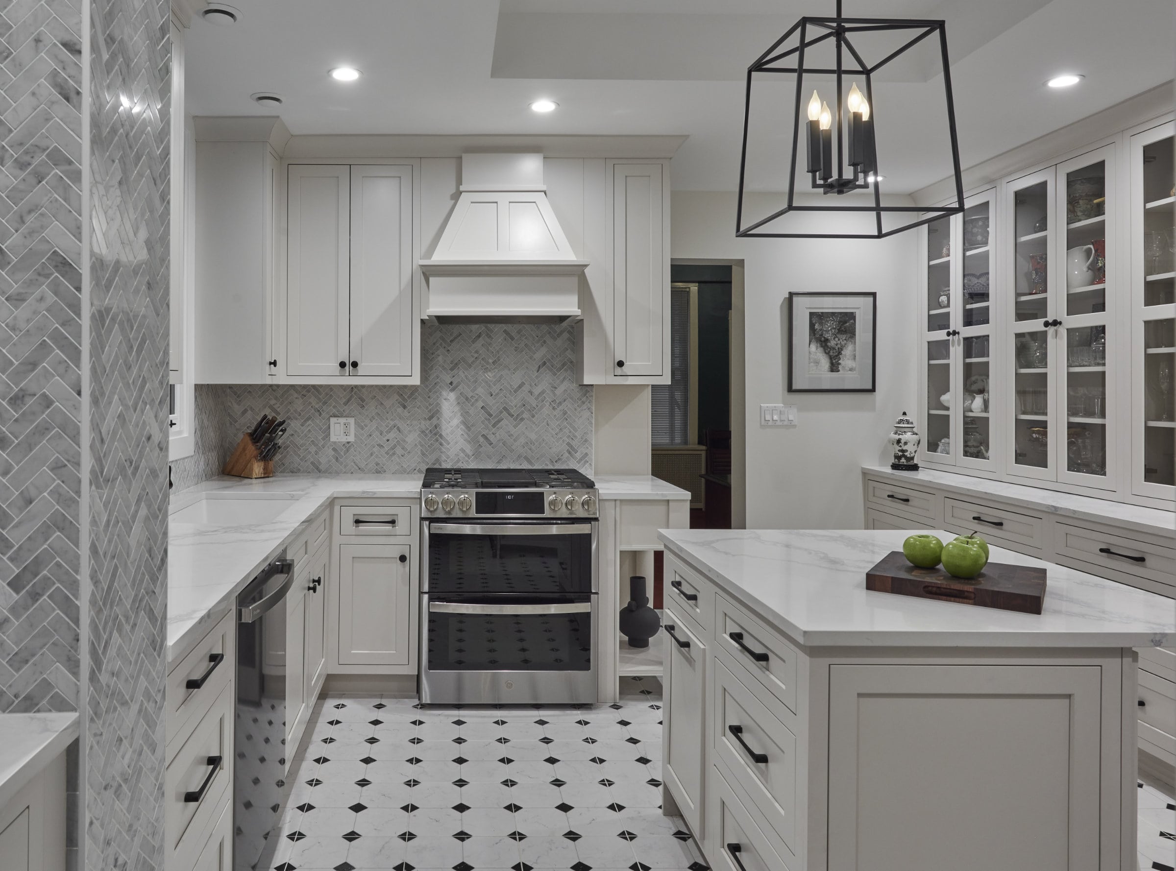 a kitchen with white cabinets and black and white tiles