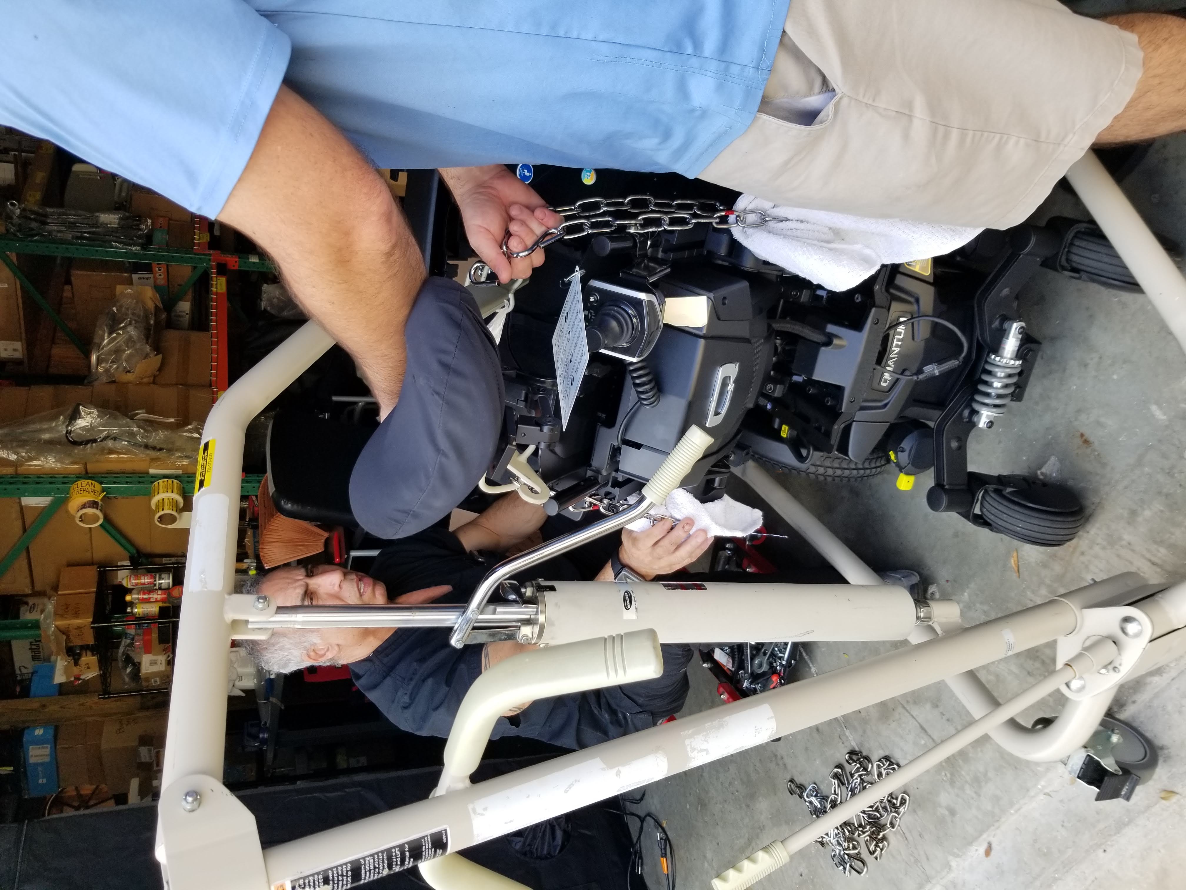 Technician adjusting a custom power wheelchair setup, demonstrating mobility solutions and repairs at MES Mobility facility.