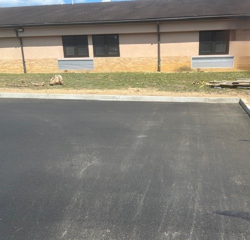 After image of an industrial site where the railroad trench has been filled in with concrete and paved over. The smooth, light-colored concrete surface now covers the previously visible trench, creating a neat and uniform appearance. The area looks clean and well-maintained, indicating the successful completion of the renovation project. Visible sections of construction equipment and safety barriers in the background further emphasize the recently finished work.