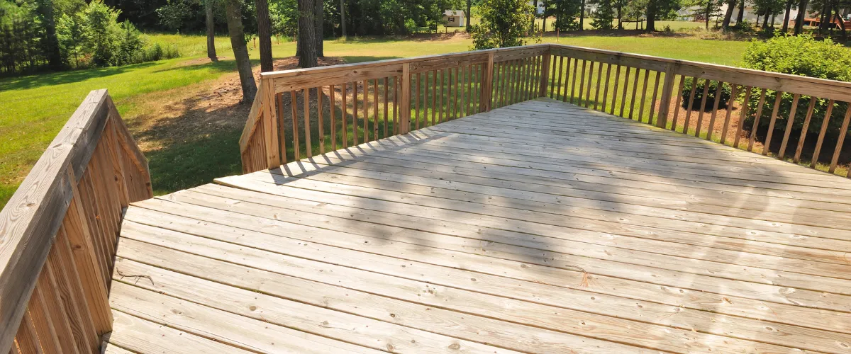 Empty wooden deck in natural finish overlooking grassy backyard area. Empty wooden deck in natural finish overlooking grassy backyard area.
