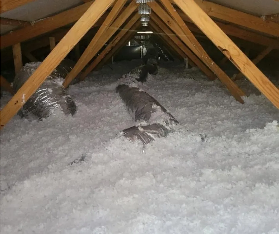 Worker blowing insulation into attic