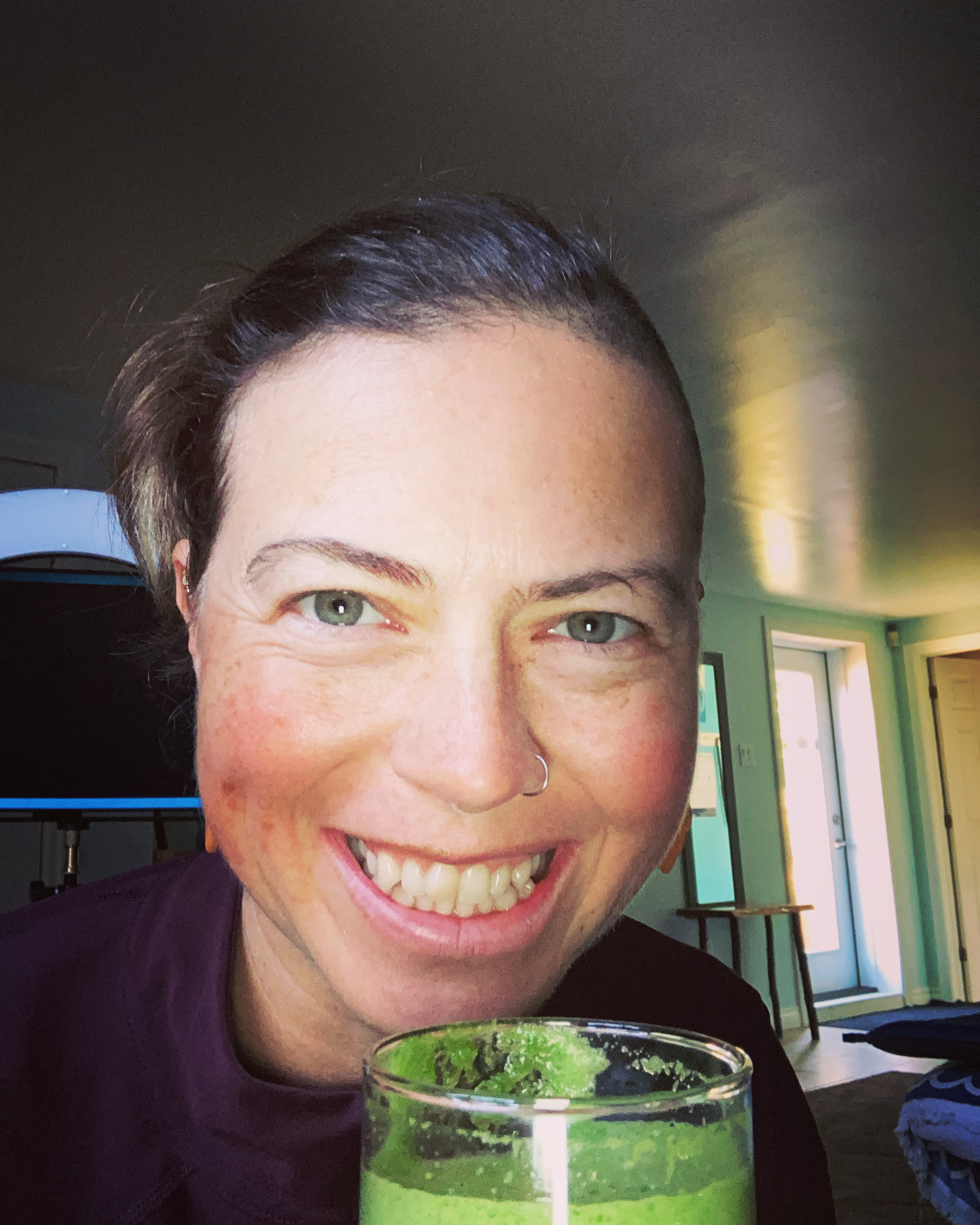 lady smiling holding green juice jules hare holding green juice