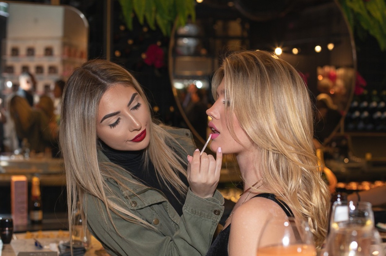 Professional makeup artist applying lipstick at a beauty brand launch event — luxury cosmetics experience in retail environment Professional makeup artist applying lipstick at a beauty brand launch event — luxury cosmetics experience in retail environment