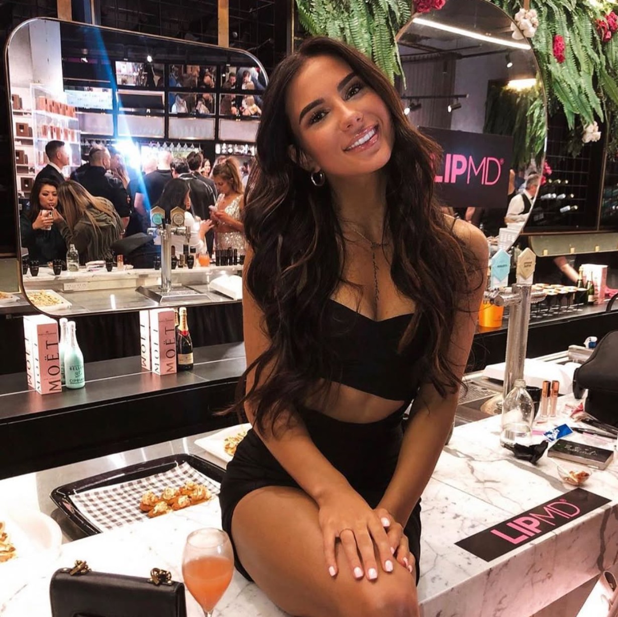 Influencer smiling at LIPMD brand launch event surrounded by beauty products and champagne — modern cosmetics marketing and experiential branding Influencer smiling at LIPMD brand launch event surrounded by beauty products and champagne — modern cosmetics marketing and experiential branding