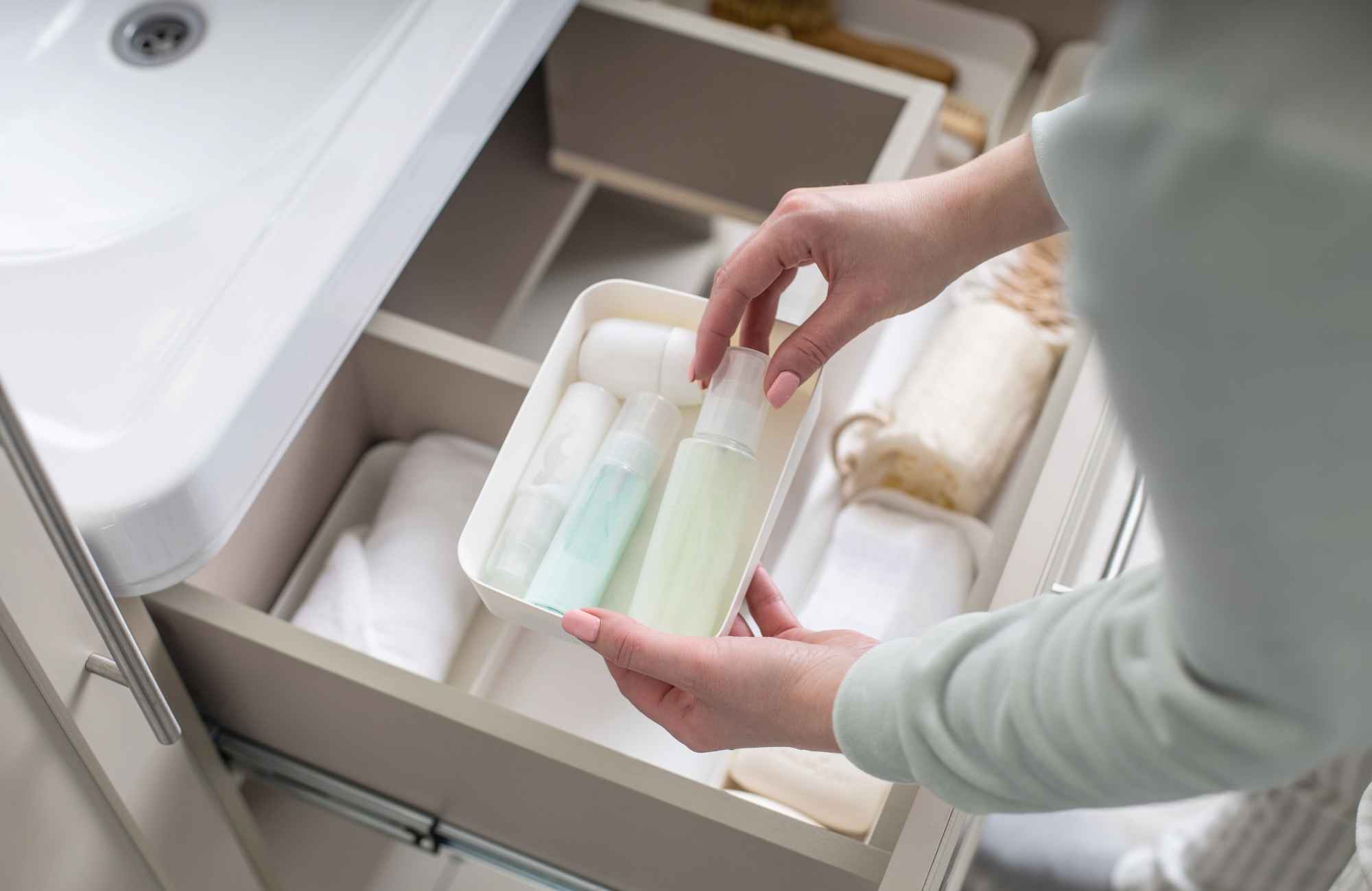 professional-home-organizers-parkville-mo-our-organizing-process-woman-putting-toiletry-items-neatly-in-bathroom-drawer-compassionate-efficient