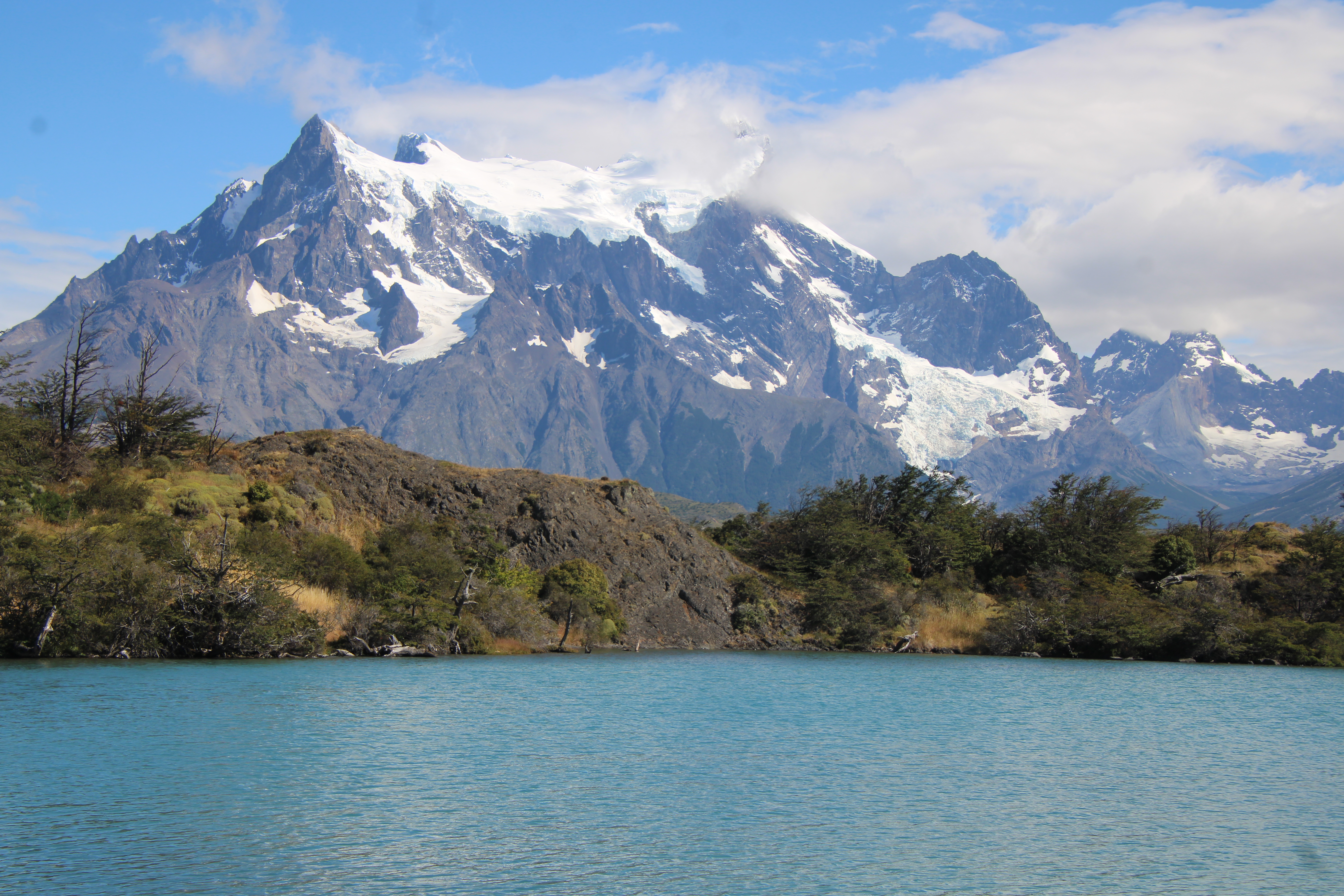 A blue lake with snow-capped mountains in the background A blue lake with snow-capped mountains in the background