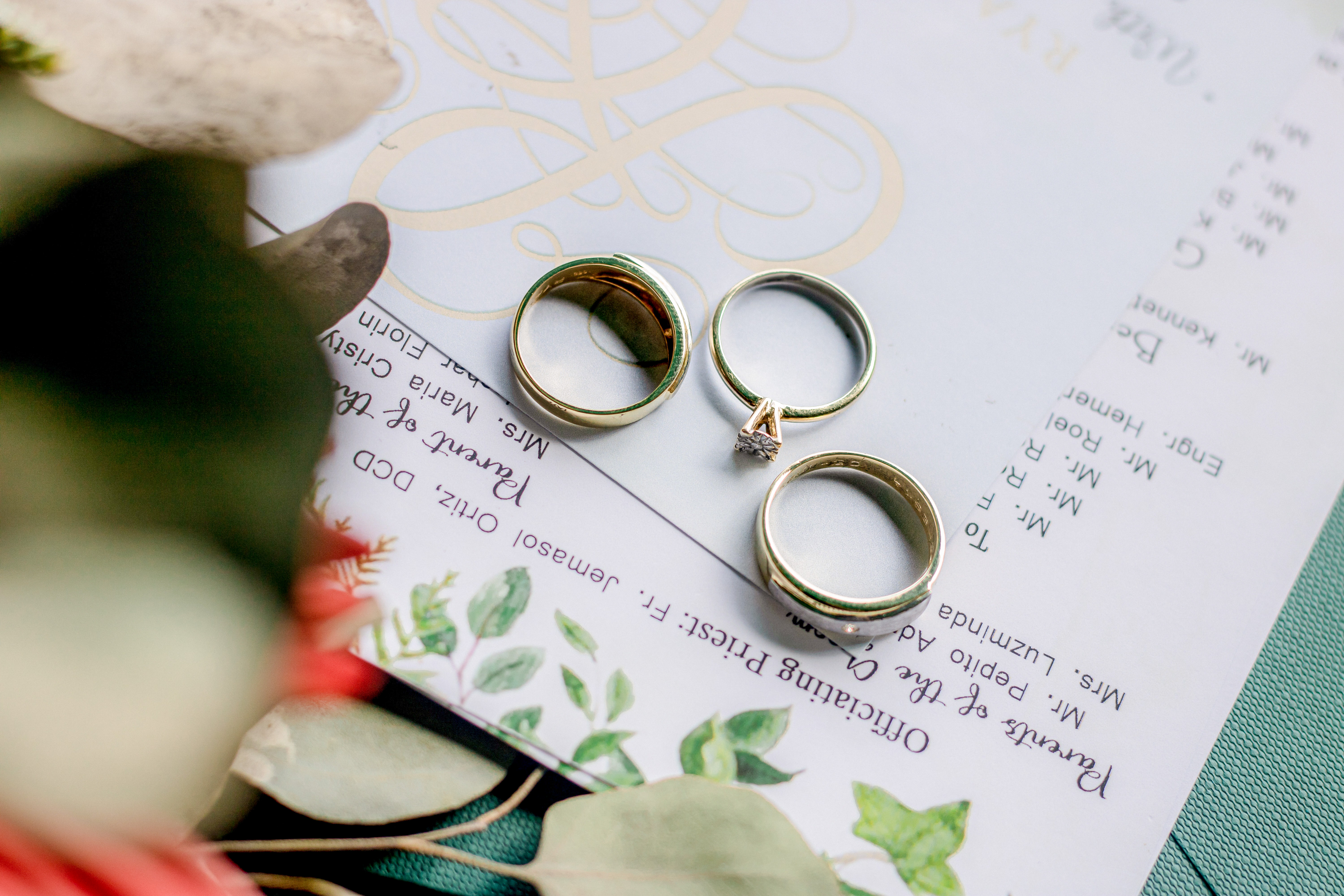 engagement ring, two wedding bands and the ceremony itinerary with bride's bouquet