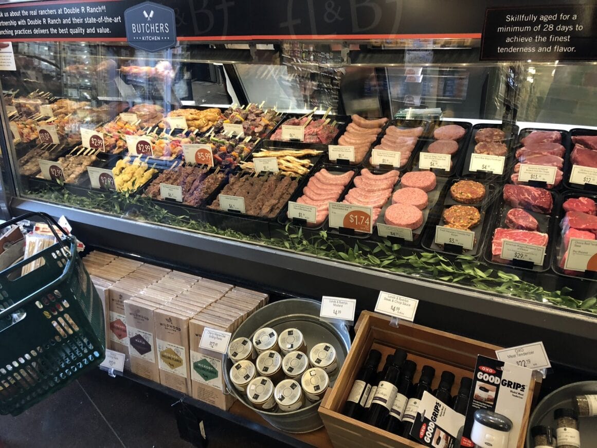 a display case with meats and drinks with cool lighting