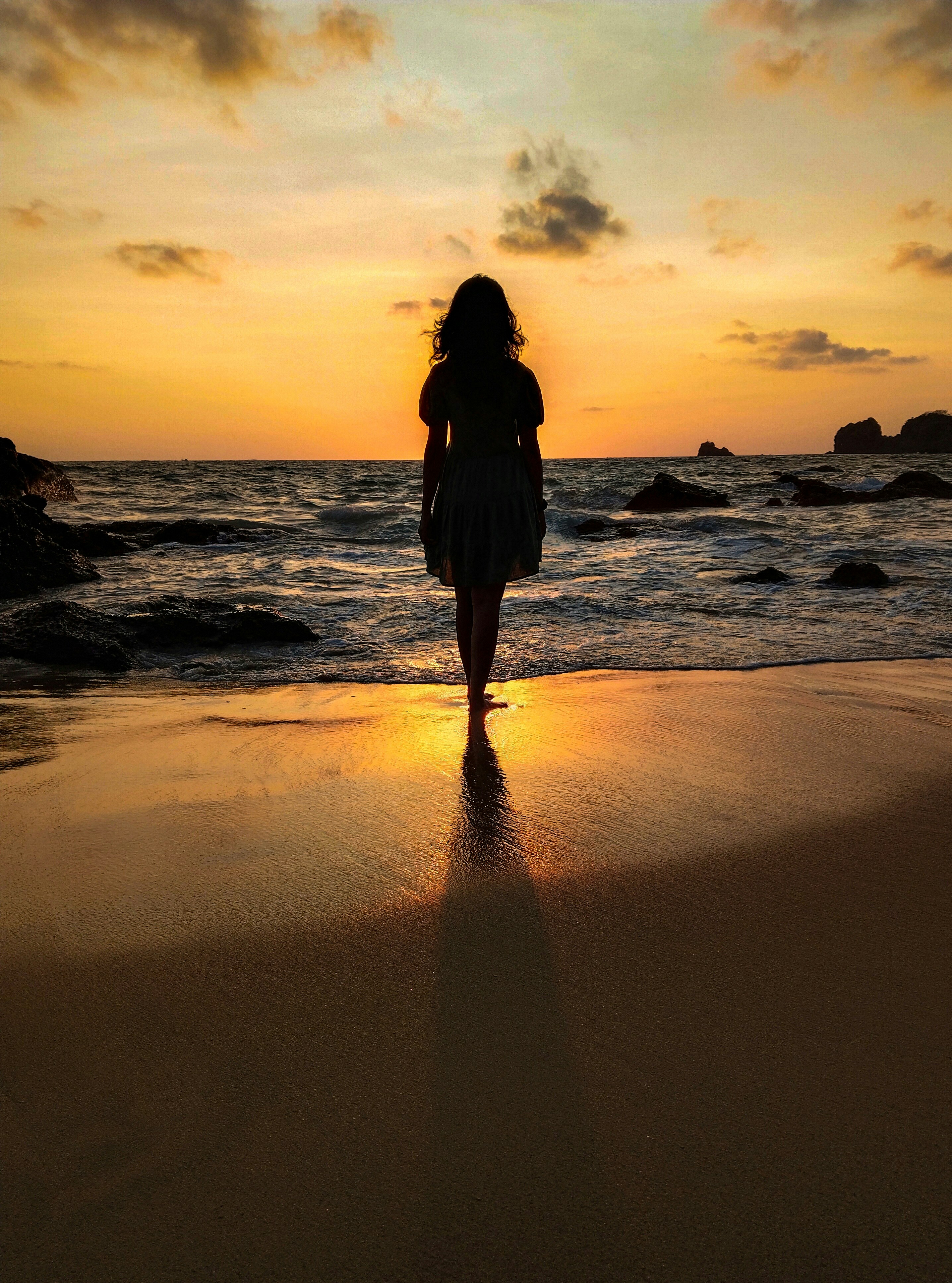 Silhouette of a woman walking the beach at sunrise