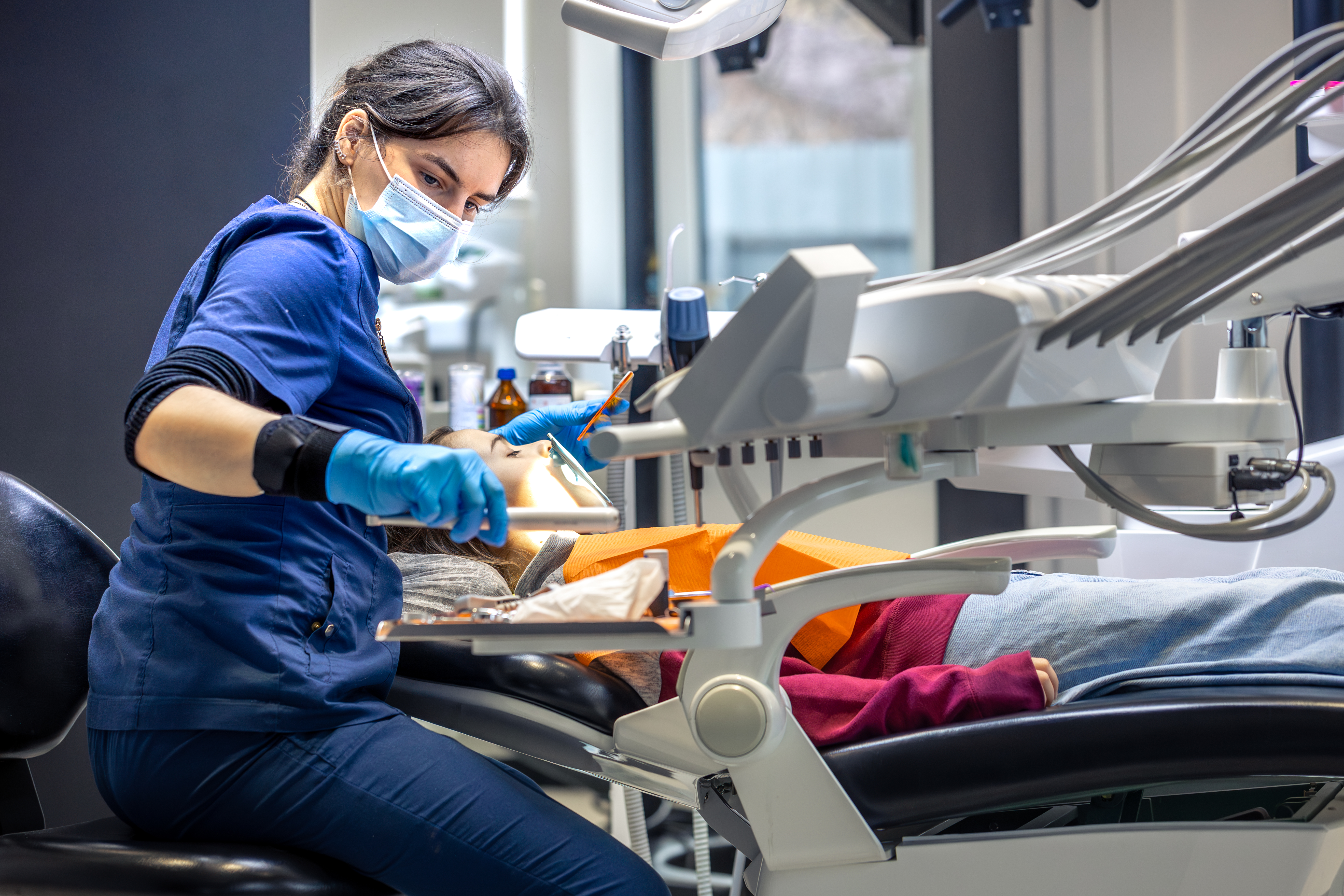 Dentist marketing concept showing a female dentist in a modern dental clinic treating a patient, highlighting professional dental care services.