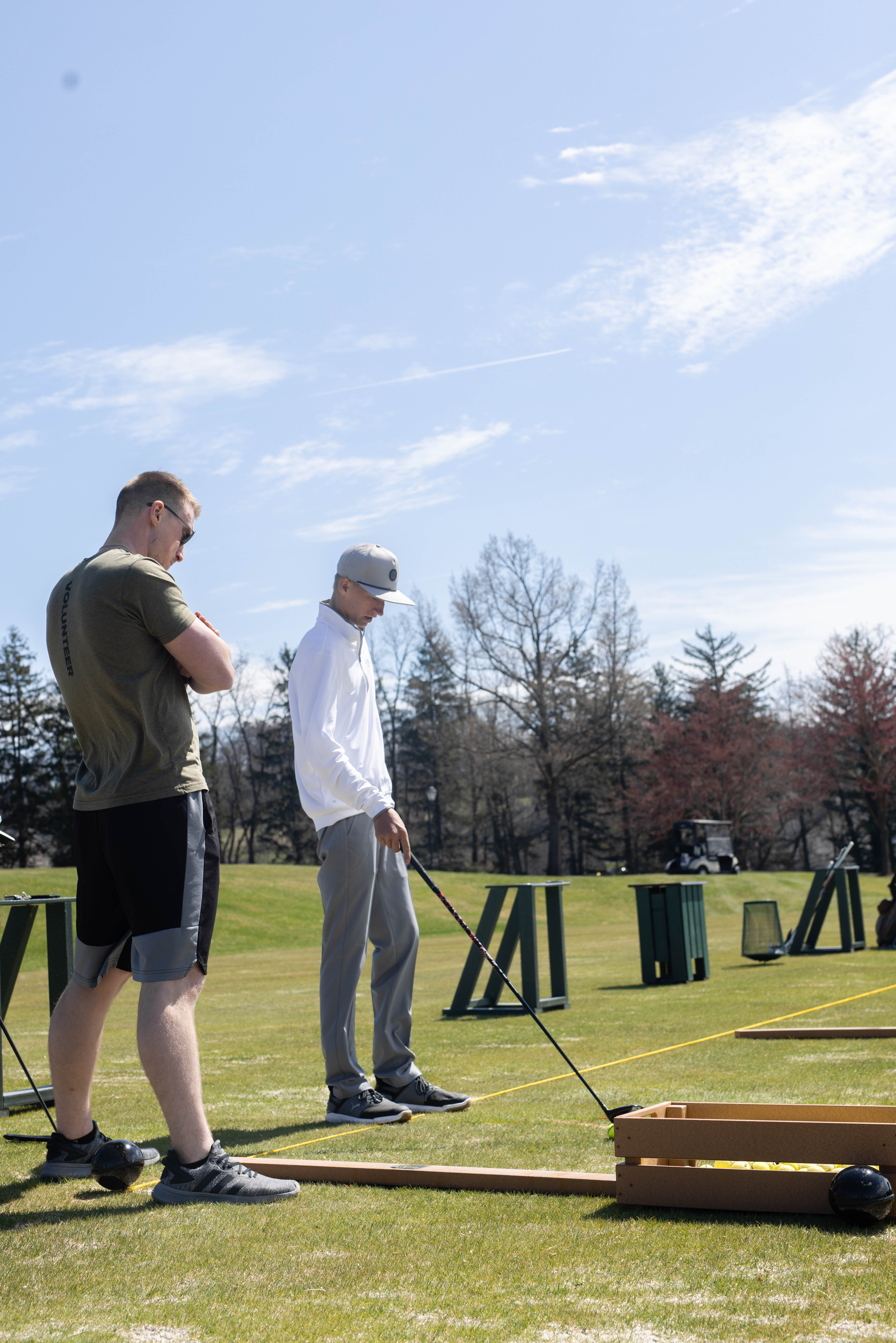 Kody Hartlaub coaching a golfer on the driving range during an outdoor mental conditioning and performance training session