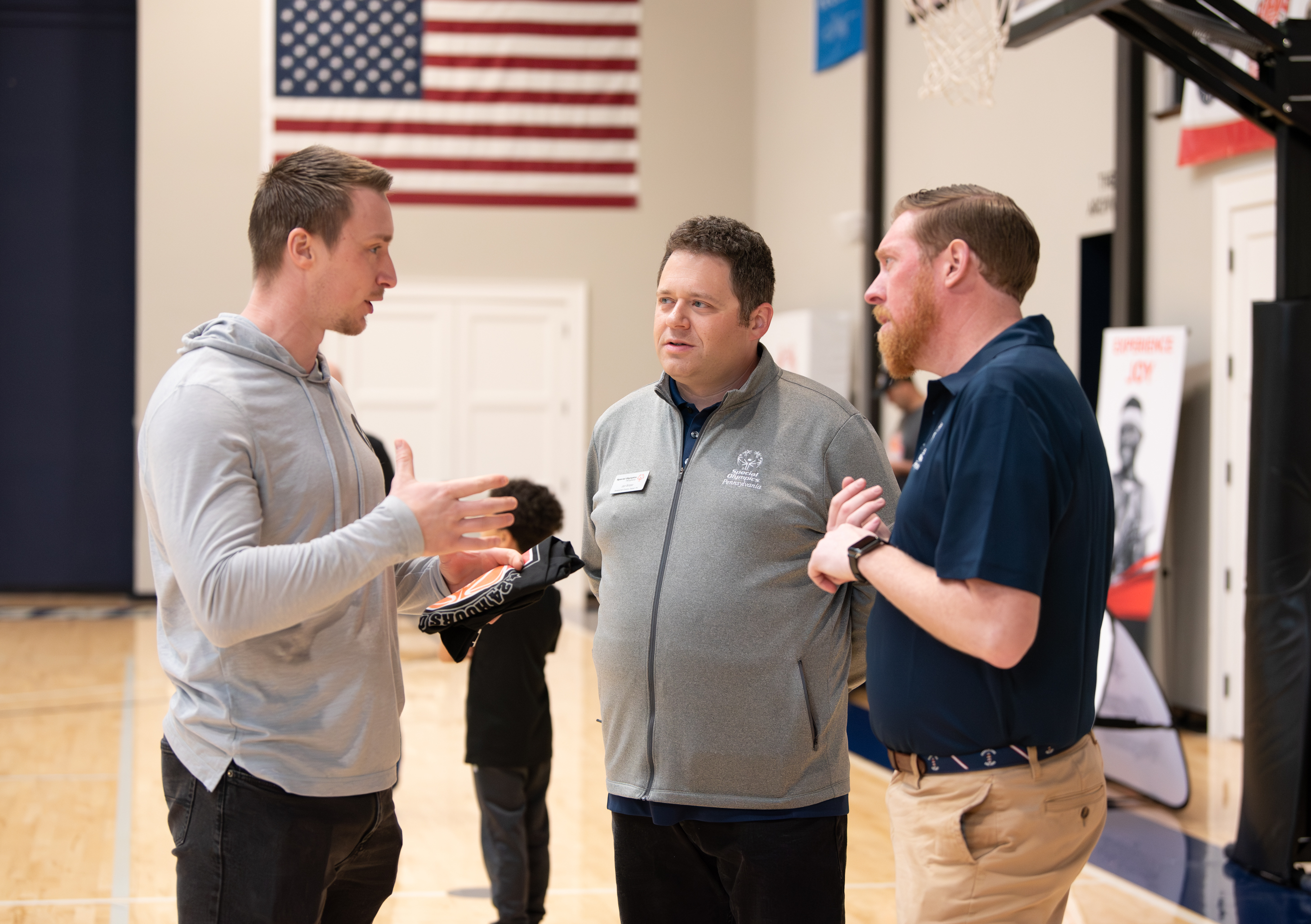 Kody Hartlaub speaking with two sports professionals at a basketball event, discussing leadership, teamwork, and mental conditioning strategies