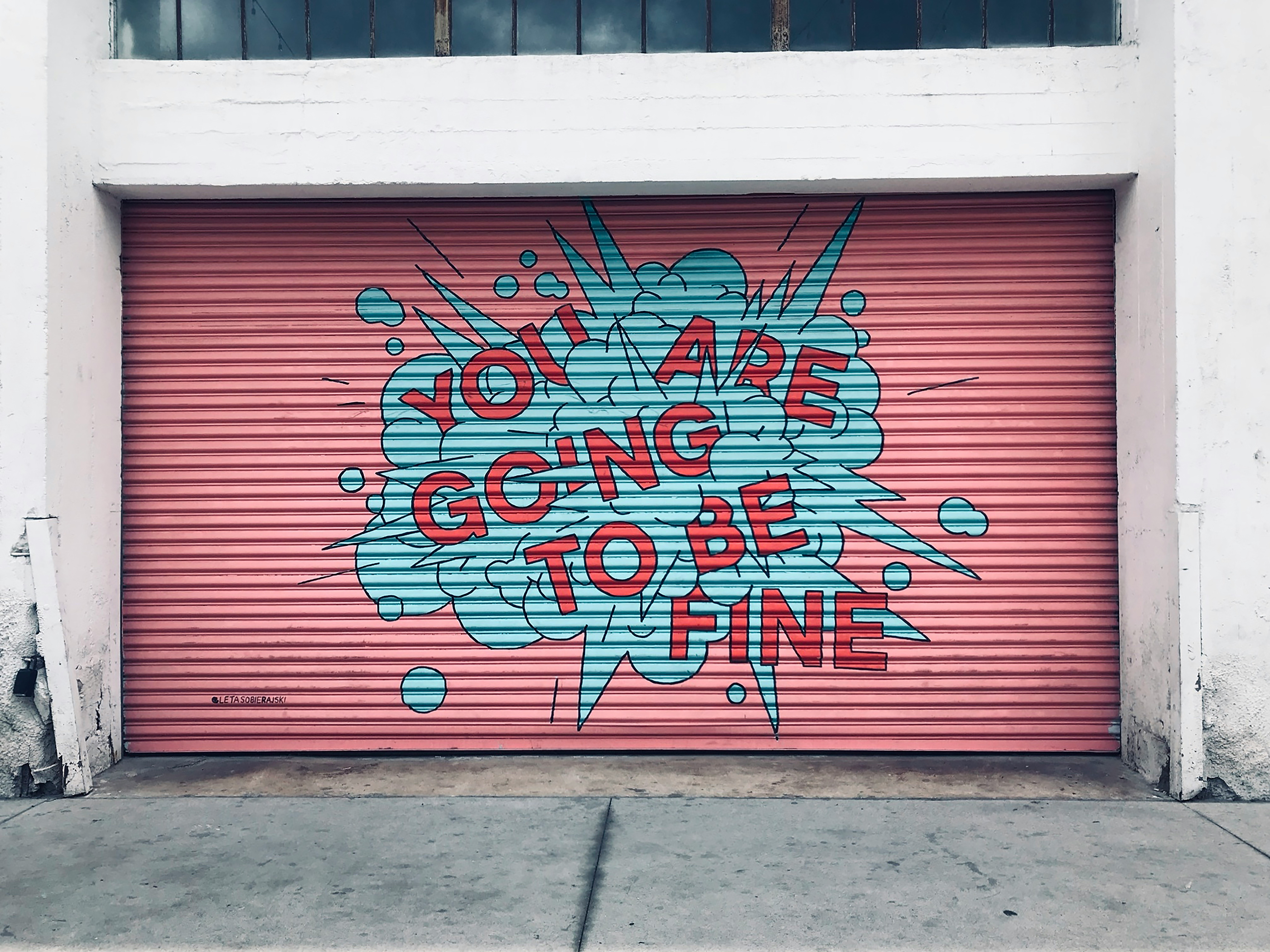 A graffiti-decorated garage door featuring the phrase, "You are going to be fine," promoting an uplifting sentiment in urban art. A graffiti-decorated garage door featuring the phrase, "You are going to be fine," promoting an uplifting sentiment in urban art.