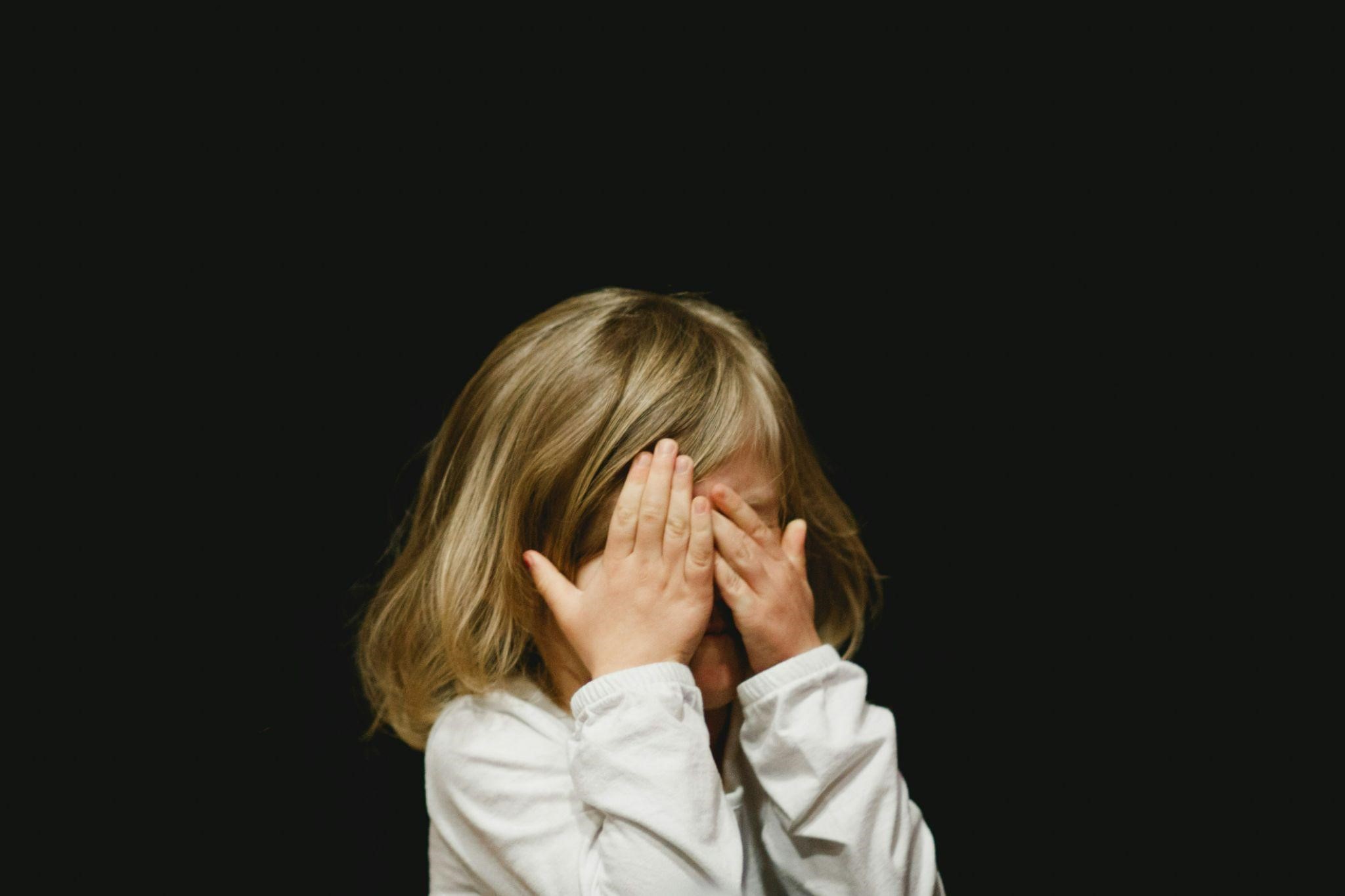 A little girl covers her face with her hands, conveying a sense of shyness or surprise. A little girl covers her face with her hands, conveying a sense of shyness or surprise.
