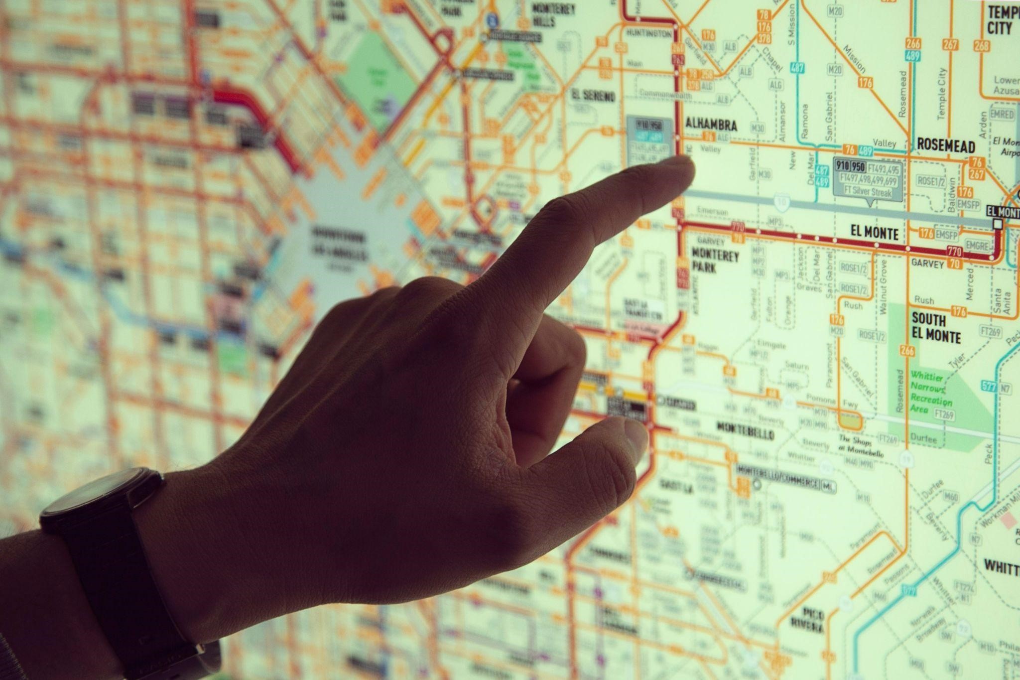A person points at a digital map displayed on a screen, indicating a specific location or route. A person points at a digital map displayed on a screen, indicating a specific location or route.