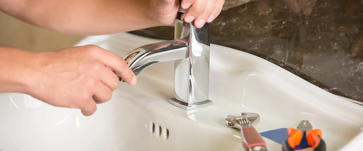 Plumber installing or tightening a bathroom faucet assembly