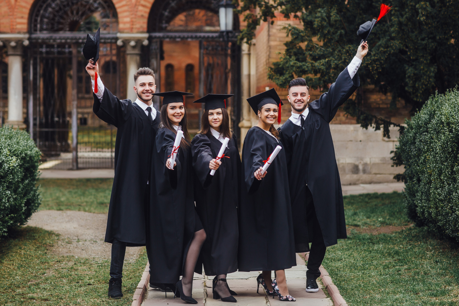 Students in graduation gowns tossing their caps in the air