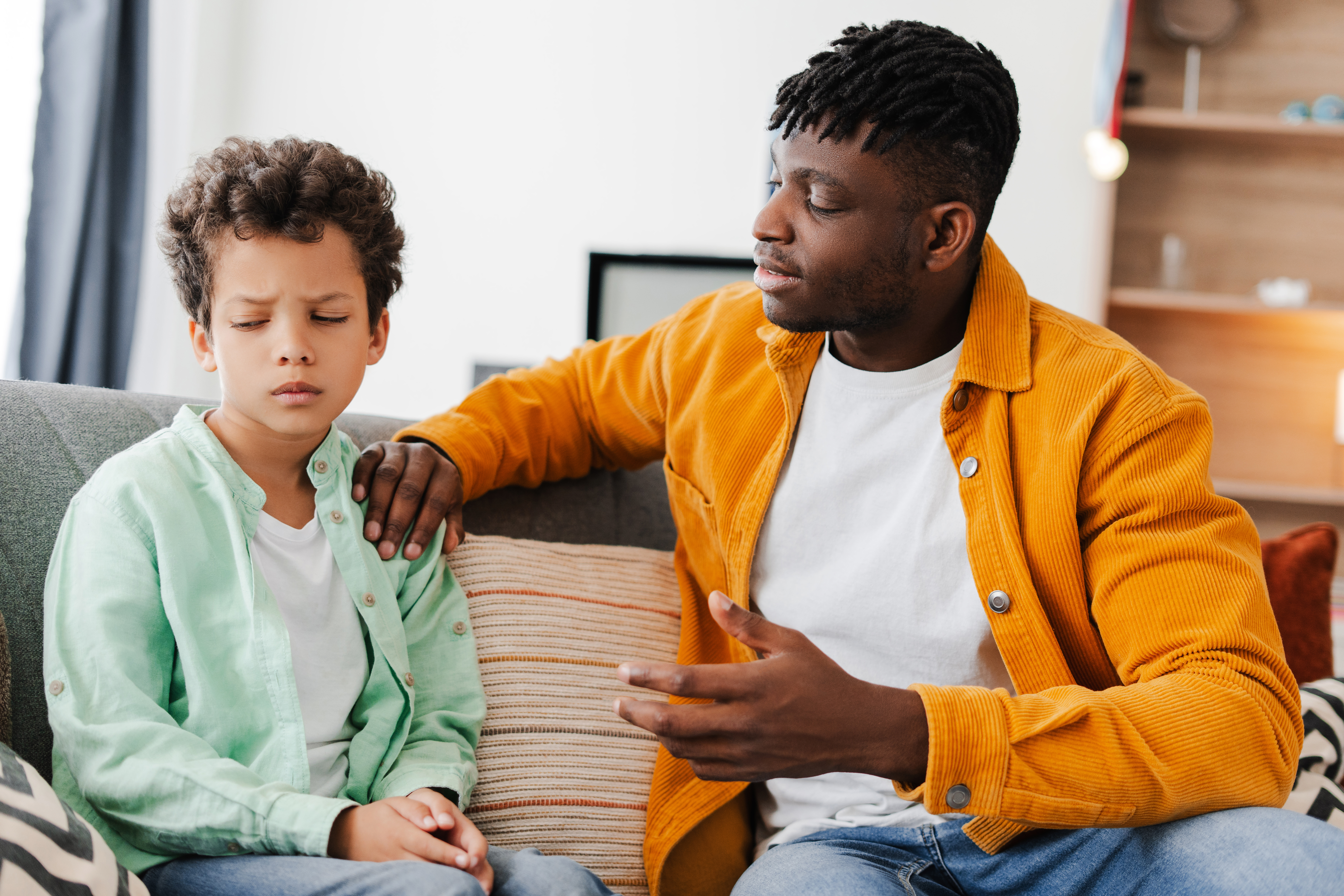 A father is calmly talking to his son, maintaining a steady and consistent approach.